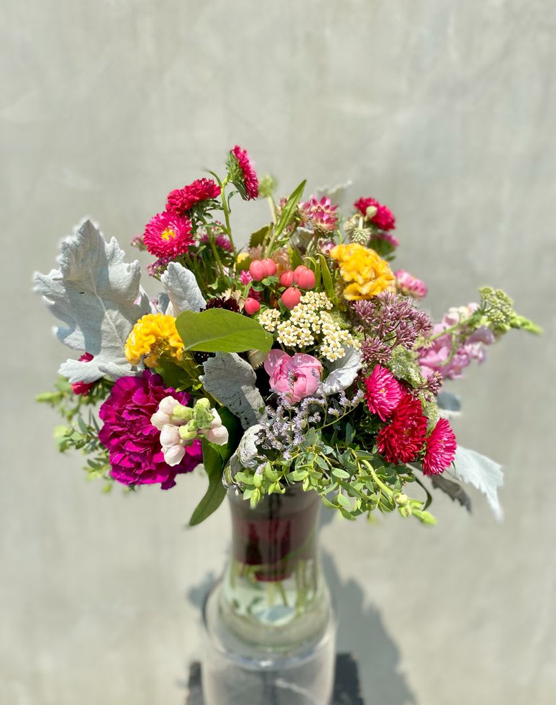 Glorious Wild - Floral Arrangement includes, red matsumoto,  pink coffee beans, yellow cockscomb flower, dusty miller and other wildflowers all hand arranged in glass vase.