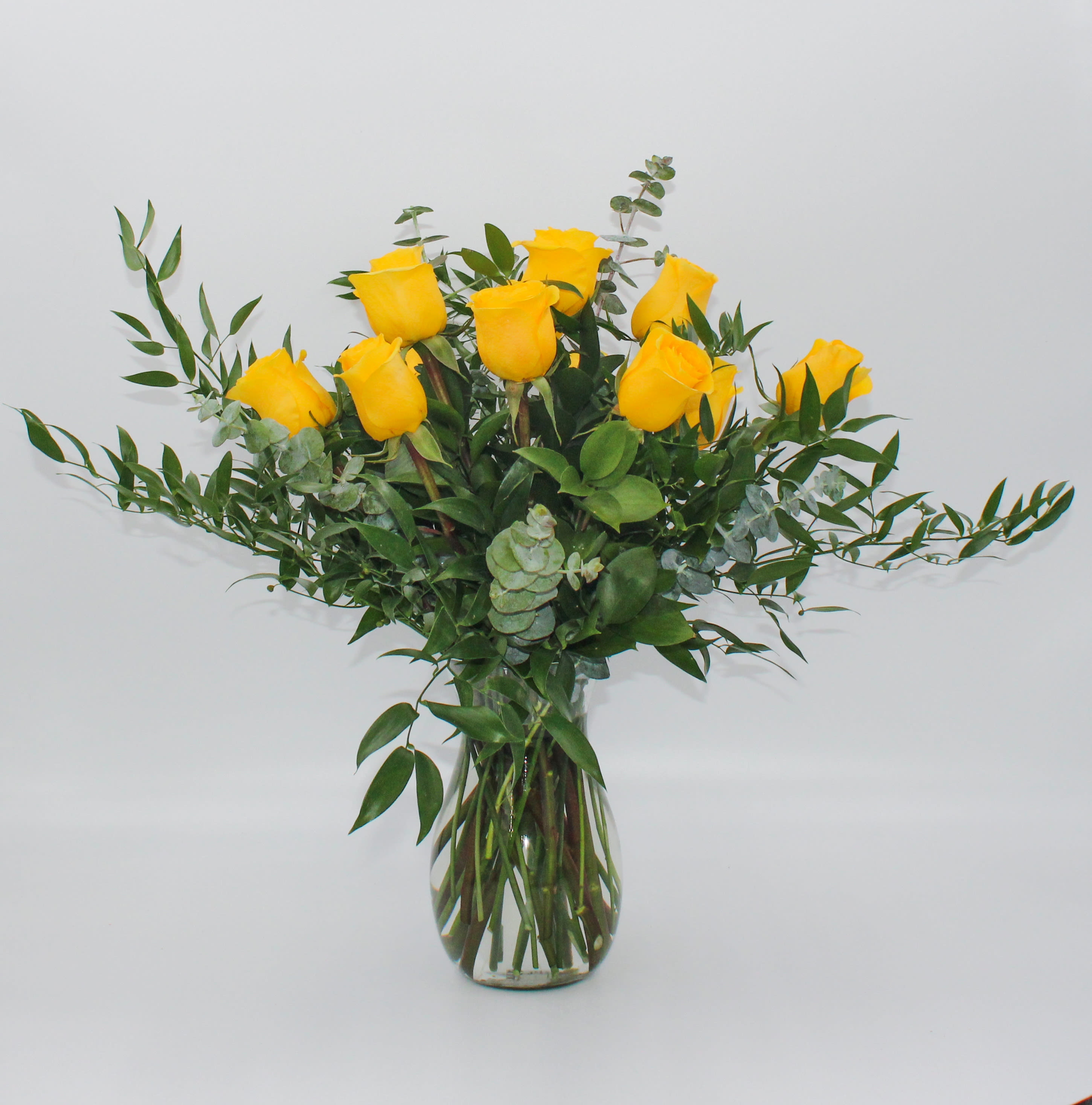 One Dozen Yellow - A Classic one dozen Ecuadorian Long Stem Yellow Roses with Ruscus and Eucalyptus and a taller clear glass vase. 
