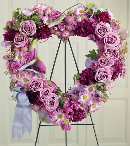 Lavender Heart - This beautiful floral heart is created using lavender gerbera daisies, lilies and roses enhanced with an assortment of lush greens and finished with a lavender bow.
