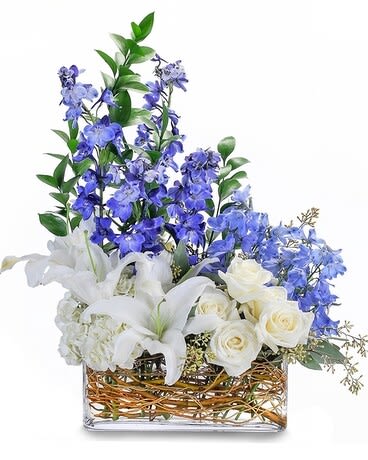 Majestic Blue - This chic bouquet includes striking blue delphinium, elegant white roses, hydrangea and majestic lilies and are designed within the curly willow filled clear glass rectangle vase. A beautifully designed centerpiece of white roses, hydrangea and shades of blue delphinium accented with seeded eucalyptus.