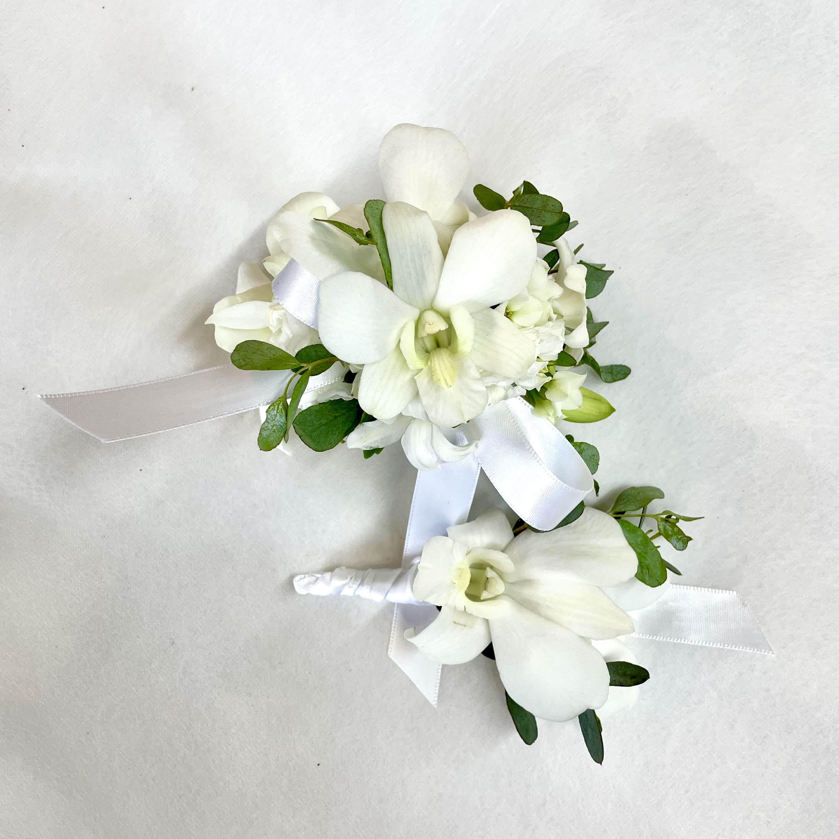 White Wrist corsage &amp; Boutonnière  - Classic white wrist corsage and boutonnière with orchid and other blooms. The corsage is fastened to a snap bracelet to accomodate all wrist sizes. The boutonnière comes with both magnets and pins for attachment depending on preference.