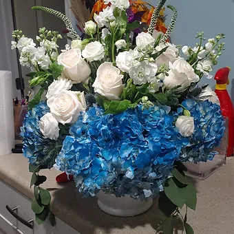 Blue Sky Deluxe - Premium Blue Hydrangea, white roses, veronica, stock, and a mix of premium white flowers and eucaluptus greenery in white footed compote.