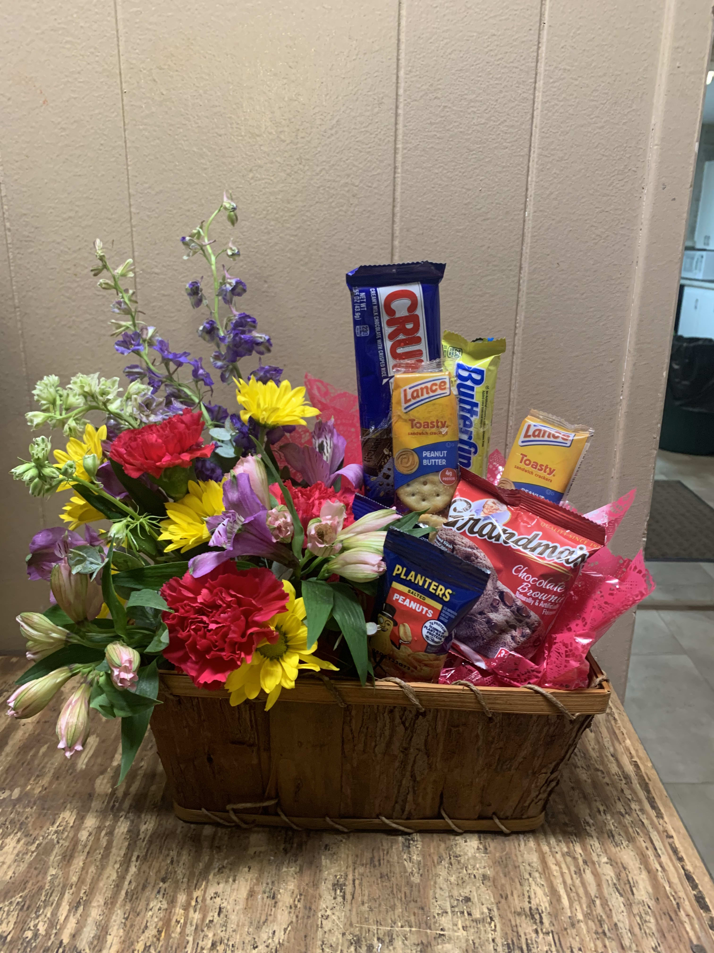 Snacks and a Smile For Mom - Fill their belly and brighten their day with this cool and unique mixture. A cherry mix of fresh flowers in a basket filled with snacks 