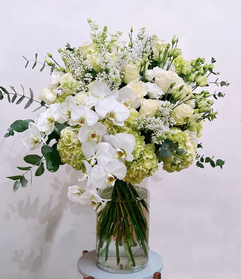 The Mother Nature Bouquet - a beautiful mix of white flowers, including hydrangeas, orchids, and roses, complemented by a touch of eucalyptus. Bring elegance to any space or gift it for a timeless expression of beauty.