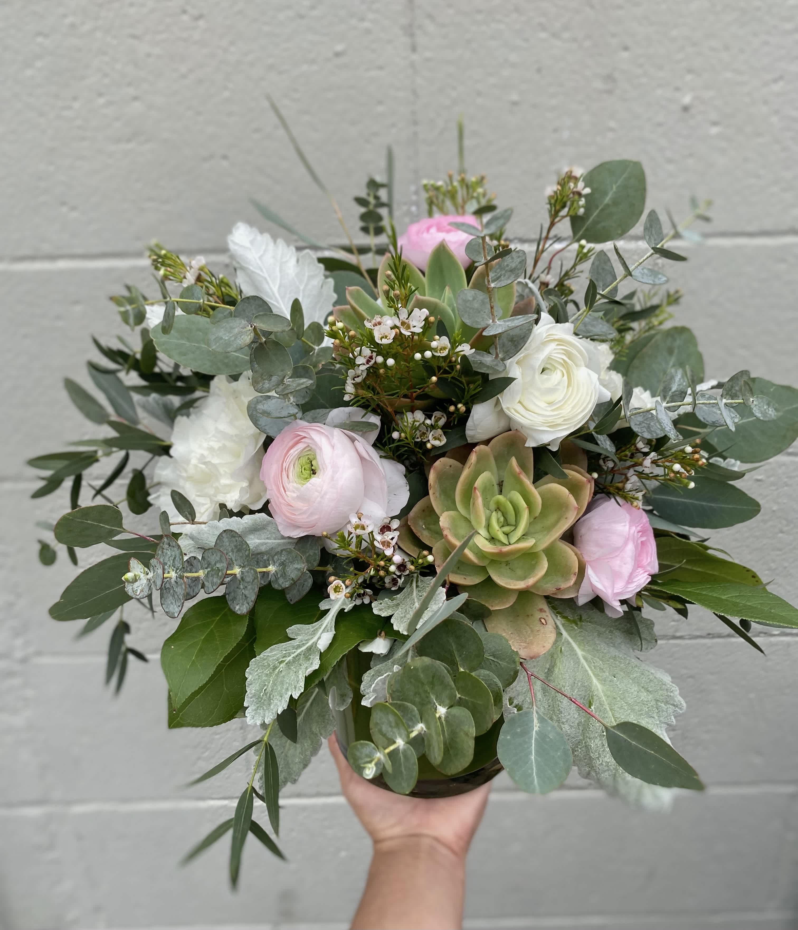The Betty The Betty - A sweet but classy arrangement perfect for a special occasion or just because! Includes ranunculus, lisianthus, succulents, dusty miller, and eucalyptus arranged in a glass vase.