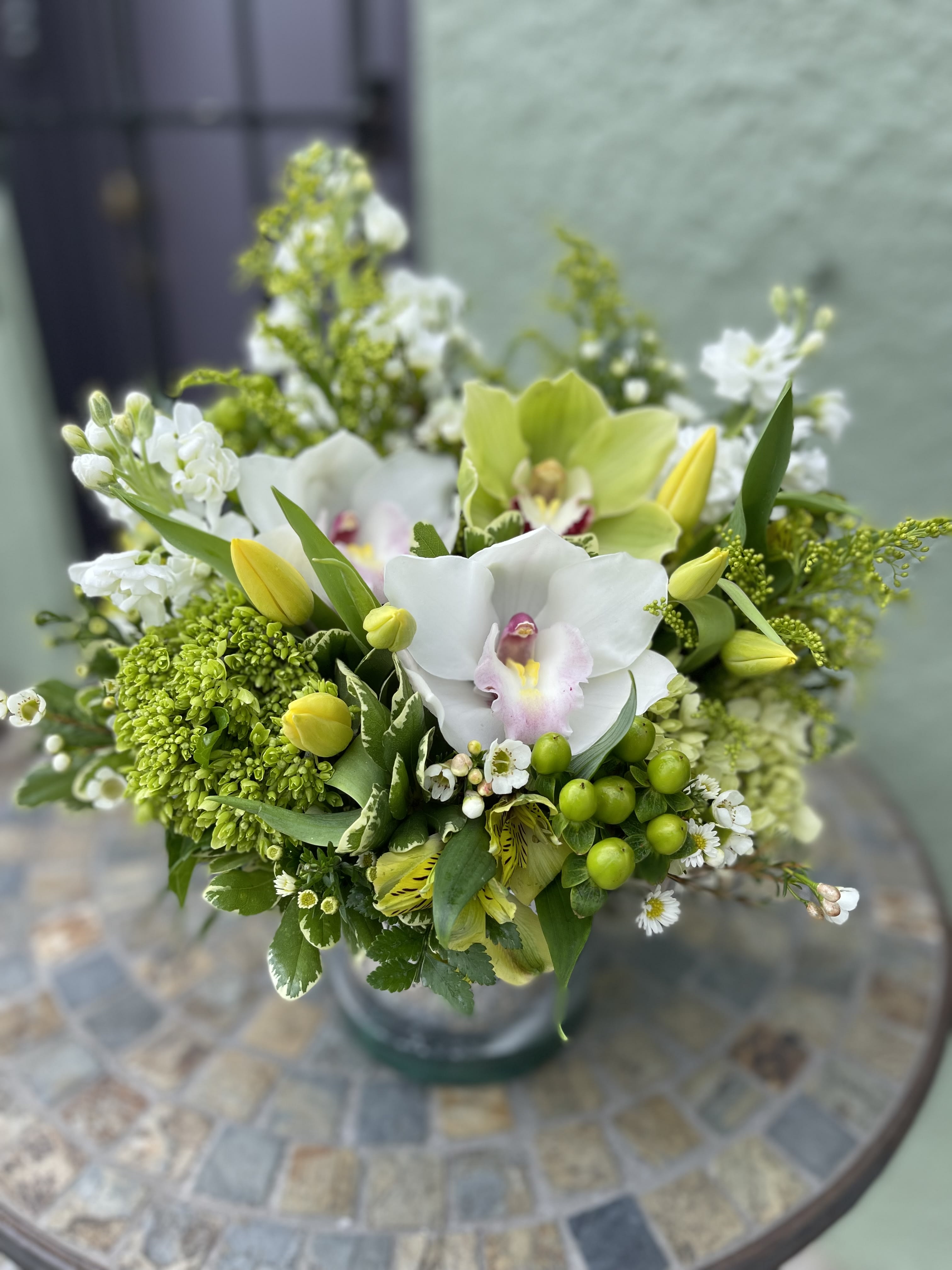 Sage - Wonderful touch of fresh green and yellow flowers such as cymbidium orchids, tulips, hypericum berries. Designed in a silver mercury glassware. It would be nice centerpiece as multiple of this as well.