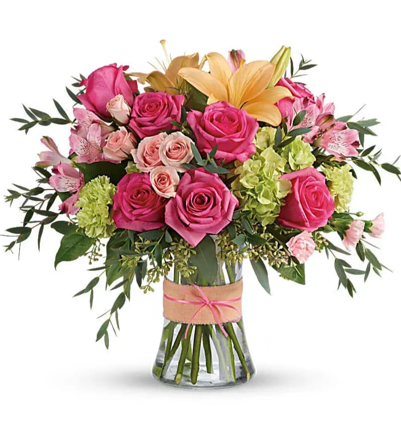 Blush Life - Put a spring in their step with this beautifully blushing bouquet of hot pink roses, soft peach lilies and fresh green hydrangea. Arranged in a graceful vase tied with a charming bow, it's a chic treat for any occasion! This sweet arrangement features green hydrangea, hot pink roses, pink spray roses, peach asiatic lilies, pink alstroemeria, green carnations, pink miniature carnations, seeded eucalyptus, parvifolia eucalyptus, and lemon leaf. Delivered in a glass gathering vase. Orientation: All-Around