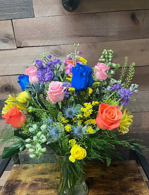 Fairy Dust Delight - A whimsical mix of multicolored roses, verdant greenery, vivid veronicas, striking delphiniums, aromatic stock, and petite spray roses. This bouquet casts a spell of charm and elegance, perfect for enchanting moments and special celebrations.      