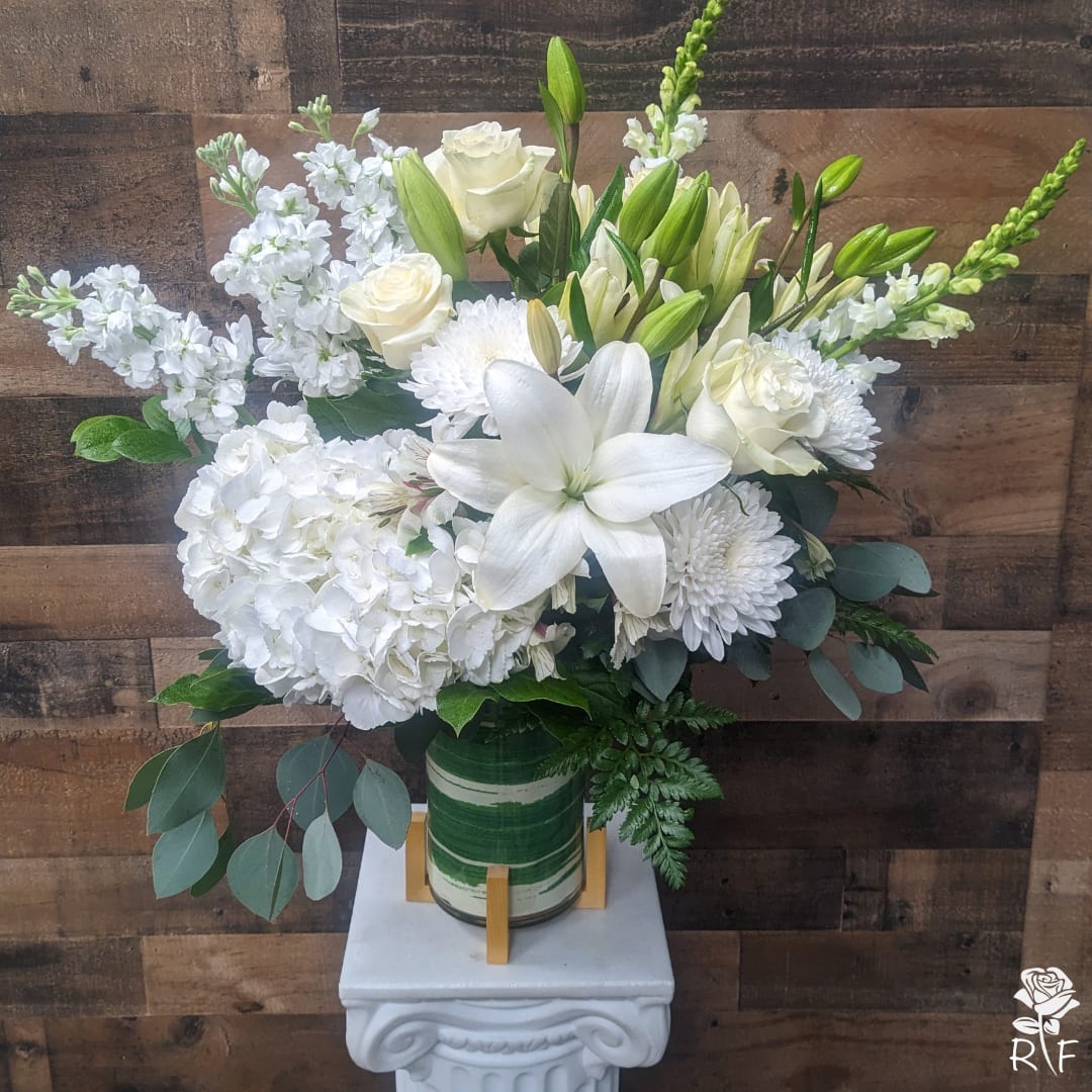 Classic All White Floral Arrangement - White flowers have a timeless elegance, which is captured in our luxurious all-white floral arrangement. A soft yet poignant mix of roses, lilies and snapdragons,hydrangea and stock is hand-gathered with touches of lush greenery inside a stylish cylinder vase. What more beautiful gift to express your love, thanks, appreciation, support—whatever is on your mind and in your heart.
