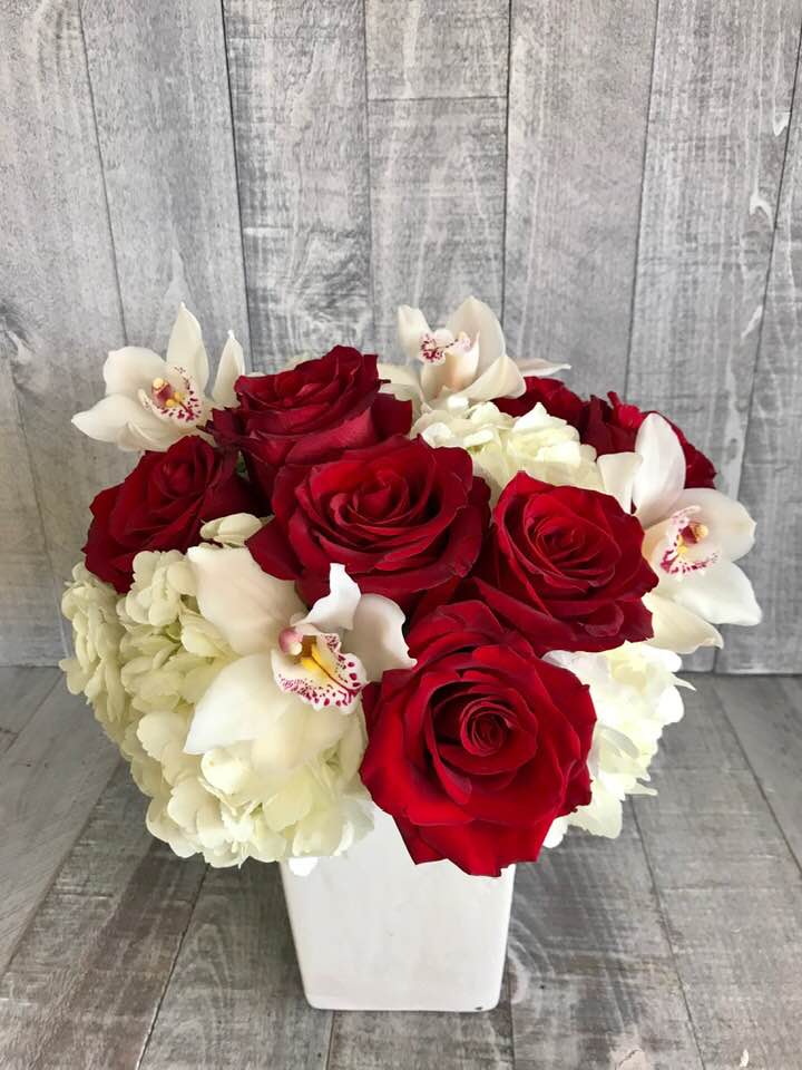 Red Roses and Orchids - Modern arrangement  with red roses, Hydrangeas and Cymbidium orchids in a nice container. Container may vary .