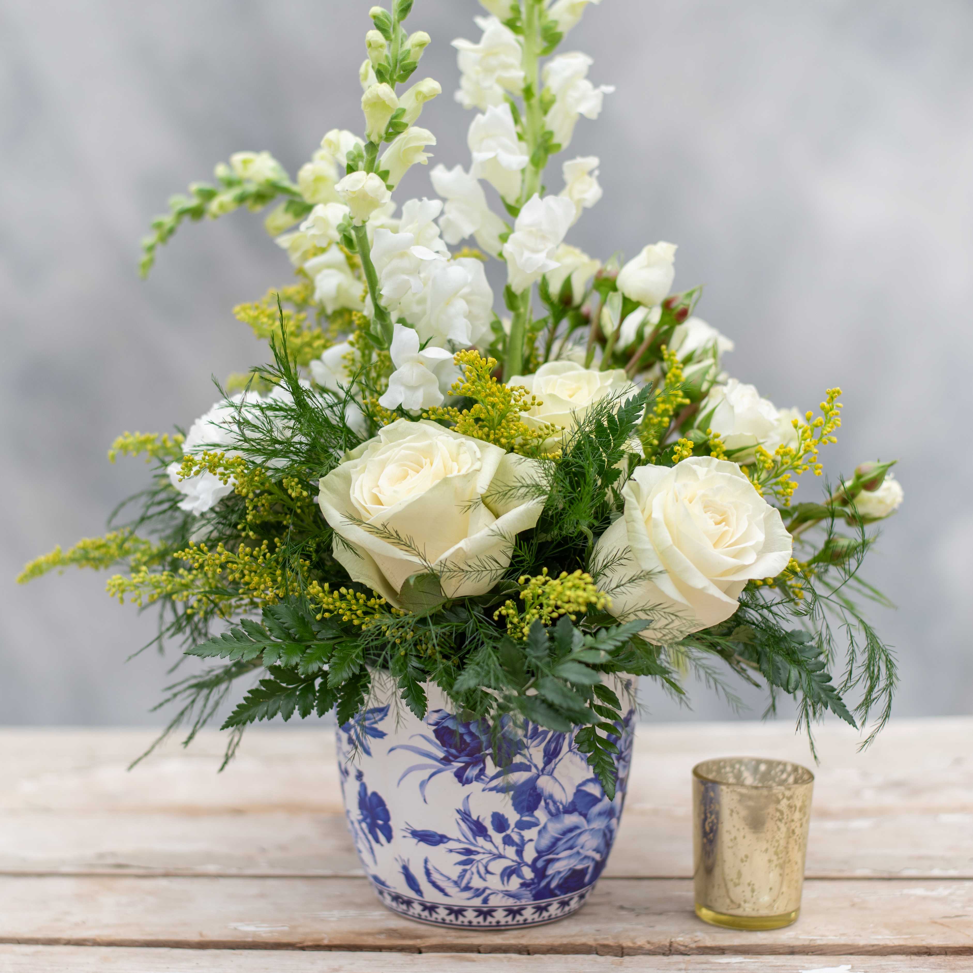 Chinoiserie - A timeless and elegant arrangement in a chinoiserie style ceramic vase.  Chinoiserie is a blend of European design with Asian influences.  We have chosen to fill this whimsical design vase with white roses and snapdragons a touch of yellow with solidago and just enough greens so as not to detract from the container.