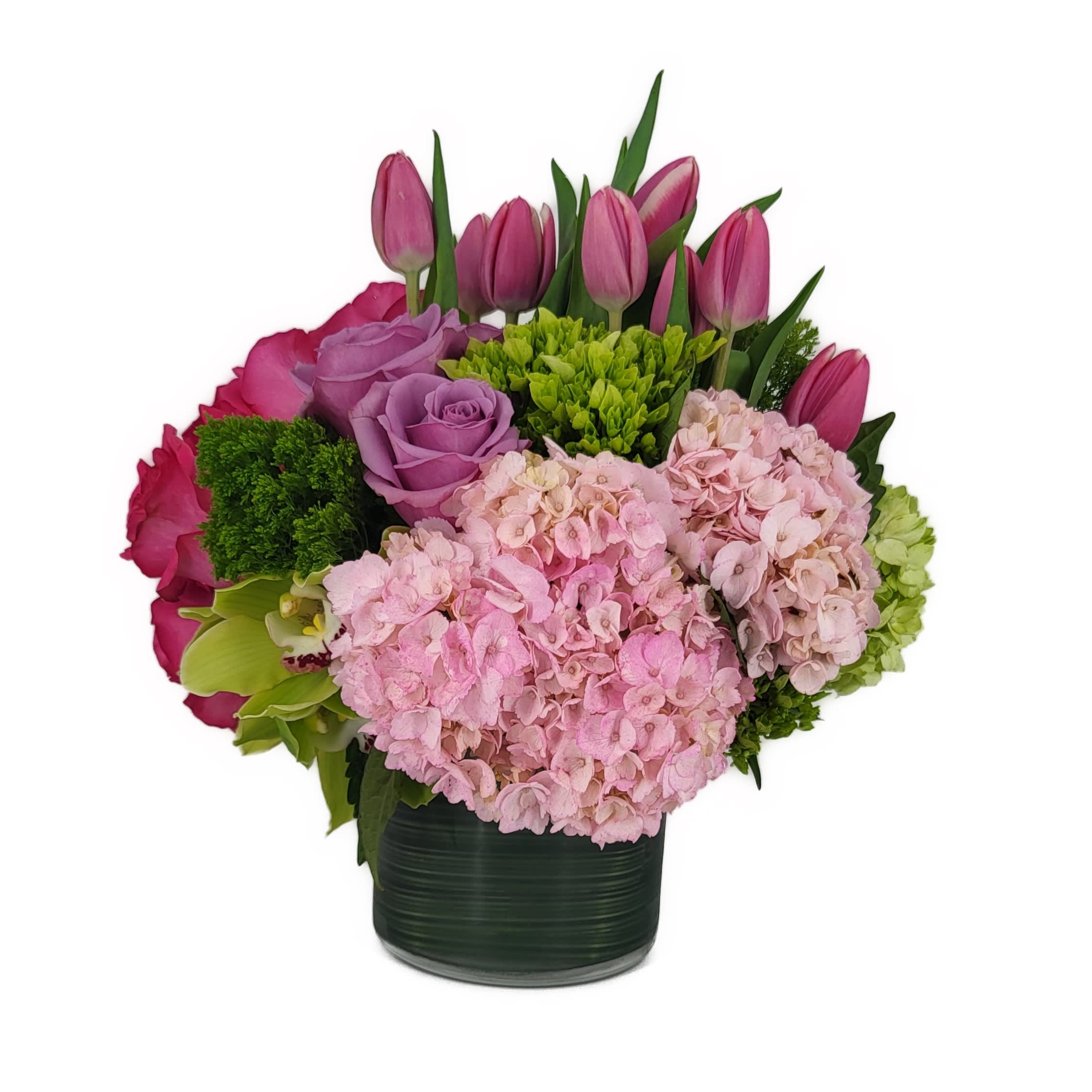New Sensation - This fantastic arrangement is a beauty and a half to behold. Overflowing with gorgeous blossoms and delivered in a leaf-lined cylinder vase, it's truly a floral fantasy.  Green and pink hydrangeas, green cymbidium orchids, hot pink and lavender roses, tulips and more are beautifully arranged in a large clear glass cylinder vase. Approximately 13&quot; W x 14&quot; Hd **Note Premium Arrangement is pictured**