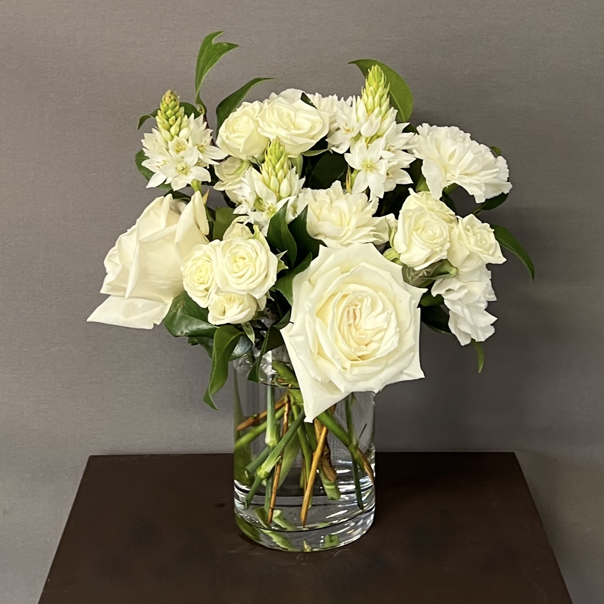 DELICATE WHITE - These delicate floral arrangement is designed using white Roses and seasonal flowers. It comes in a glass vase that is approximately 4&quot;x 8&quot;. 