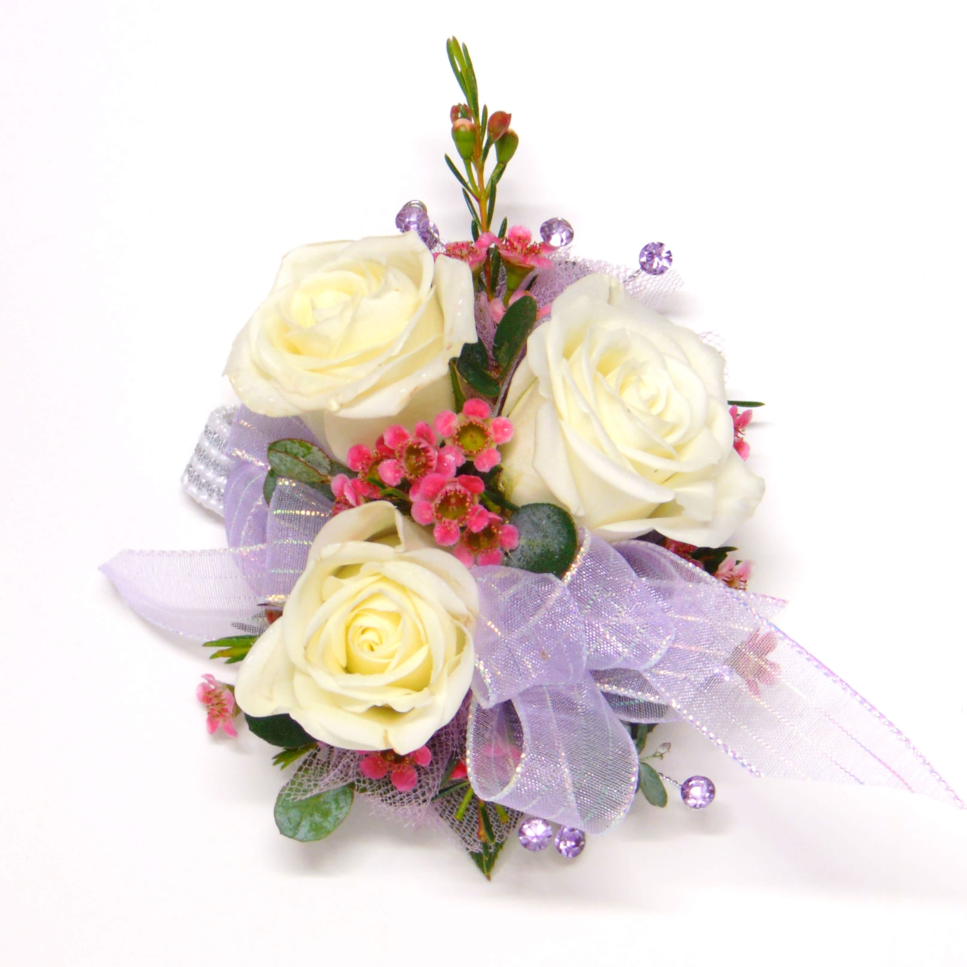 White Rose Wrist Corsage-Lavender Accents - Three white spray roses, lavender ribbon &amp; bling, purple waxflower, myrtle greens on a standard wristlet. Deluxe option includes a beaded wristlet. Includes corsage box.