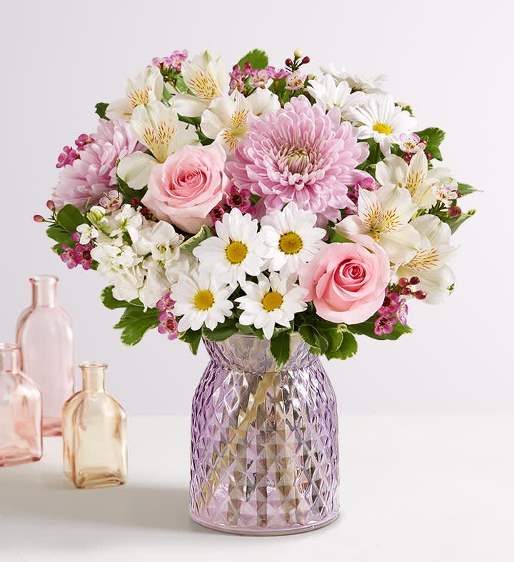 Marvelous Mom  - Lavender glass vase with pink roses, white stock, pink cremons, white alstroemeria, white daisies, and pink filler flower.  