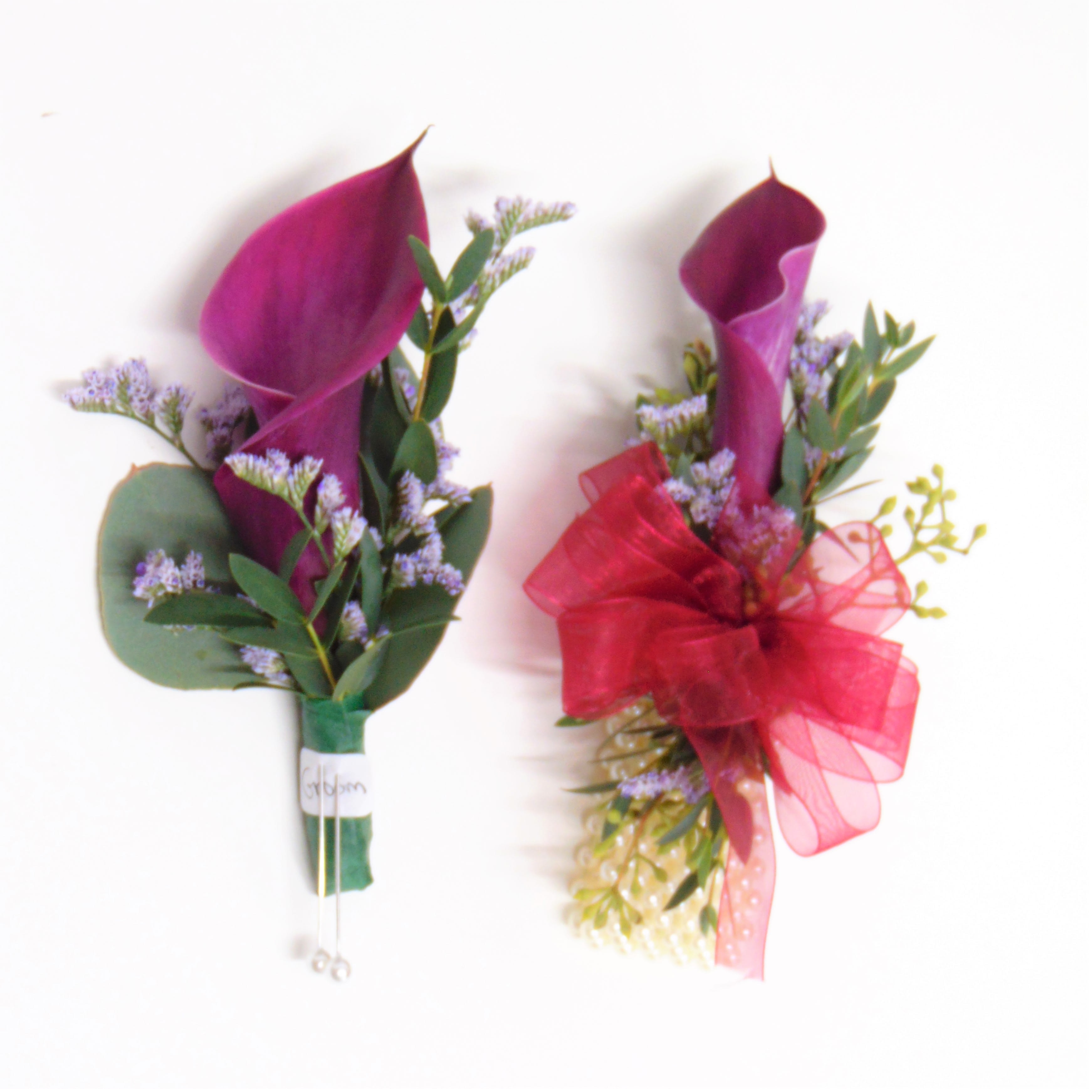 Burgundy Calla Lily Pair - Burgundy Calla Lily Boutonniere and matching burgundy Calla Lily Wrist Corsage and eucalyptus and limonium accents. Corsage is on a standard wristlet. Standard option is pictured. The deluxe option adds bling. Includes boxes.
