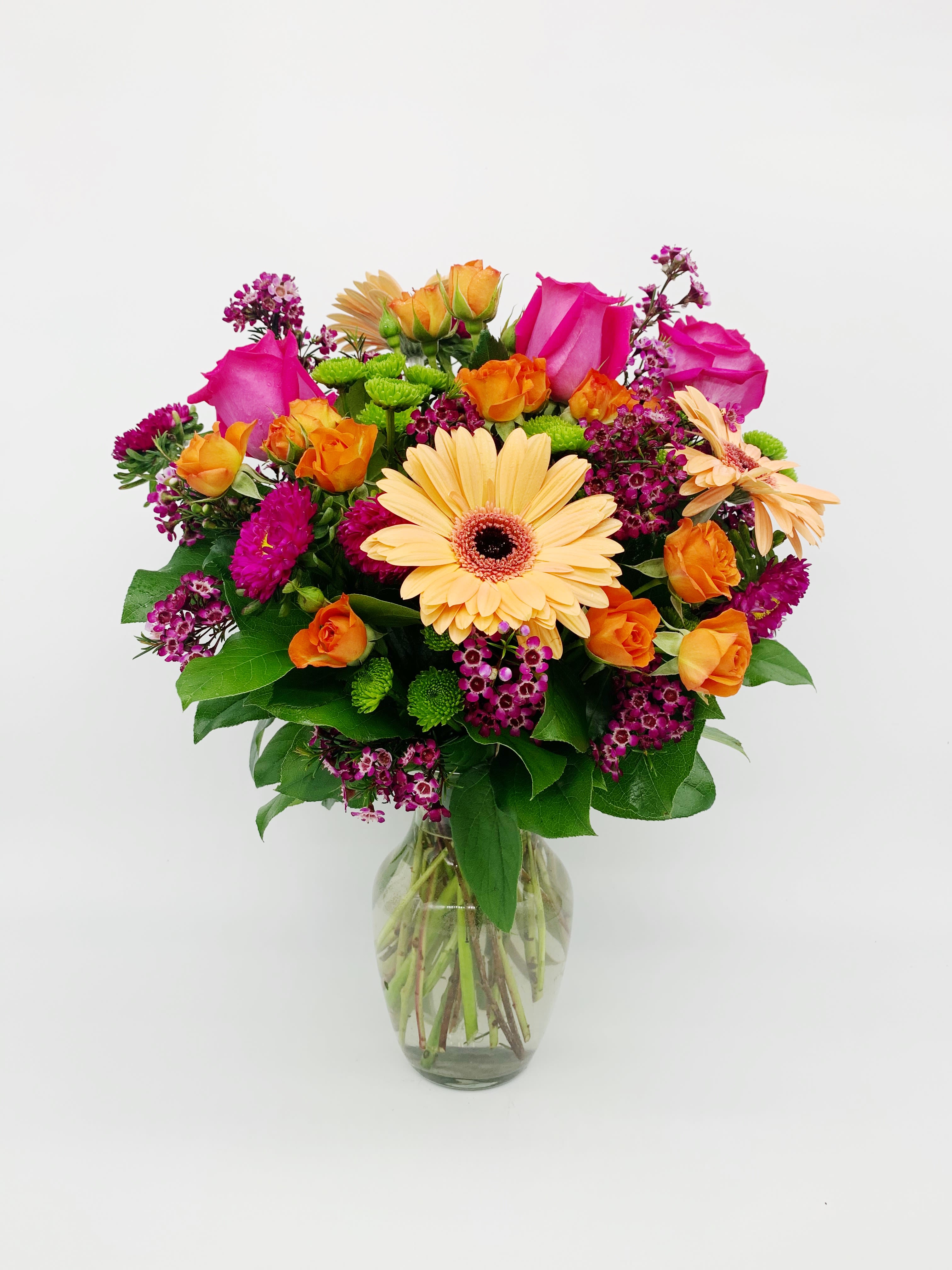 LF131 - Jeweled Sunset - A very pretty, bright and fun arrangement of orange, pink, and green flowers! These beautiful jeweled blooms go so perfect with a sunset! Nestled in a 8 1/2&quot; clear vase. Orientation:  one-sided Approximately 21 1-2&quot; H  X 18&quot; W