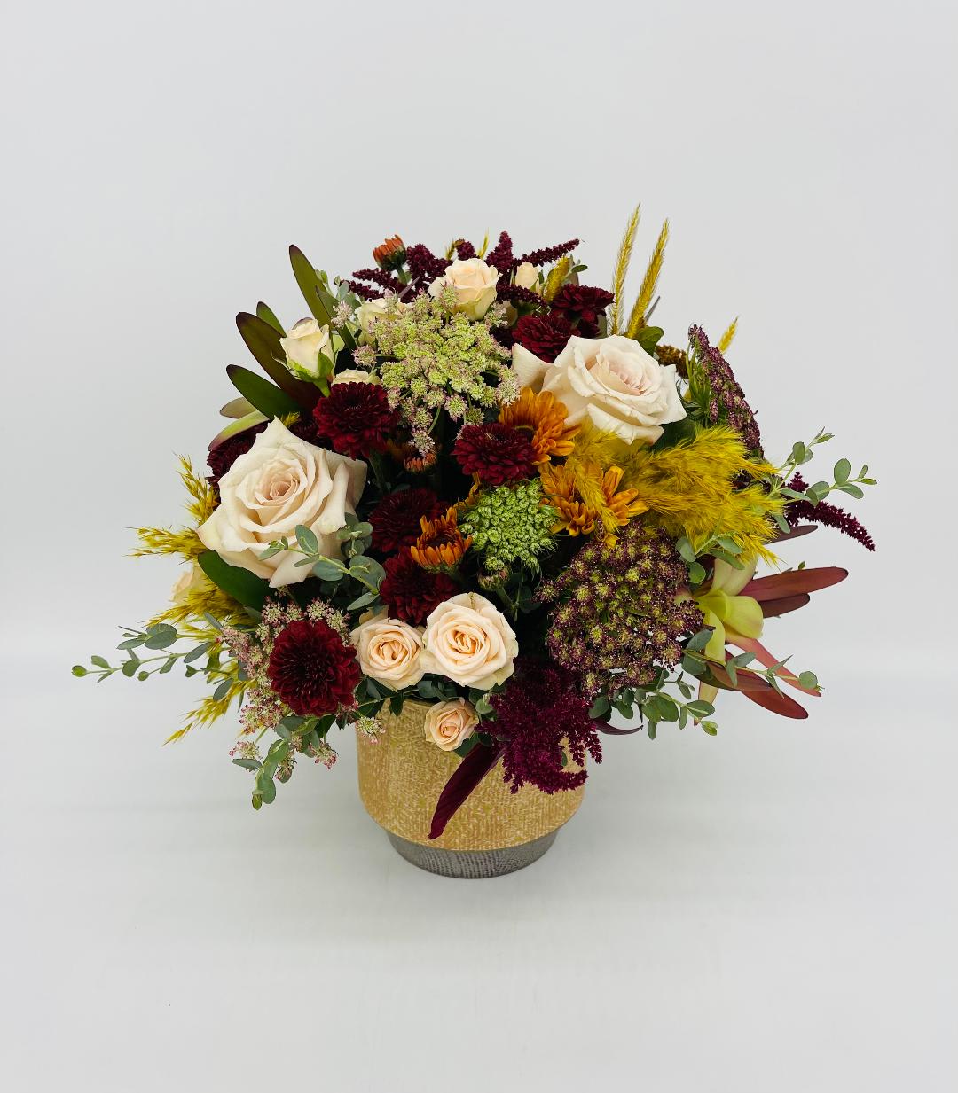 LF385  Thankfully Yours - Warm their hearts and brighten their table with this beautiful centerpiece, arranged in a round hand-glazed stoneware.   * Cream roses, spray roses, chocolate lace, leucadendron ,hydrangea and various seasonal dried     blooms.  * Orientation:  all around
