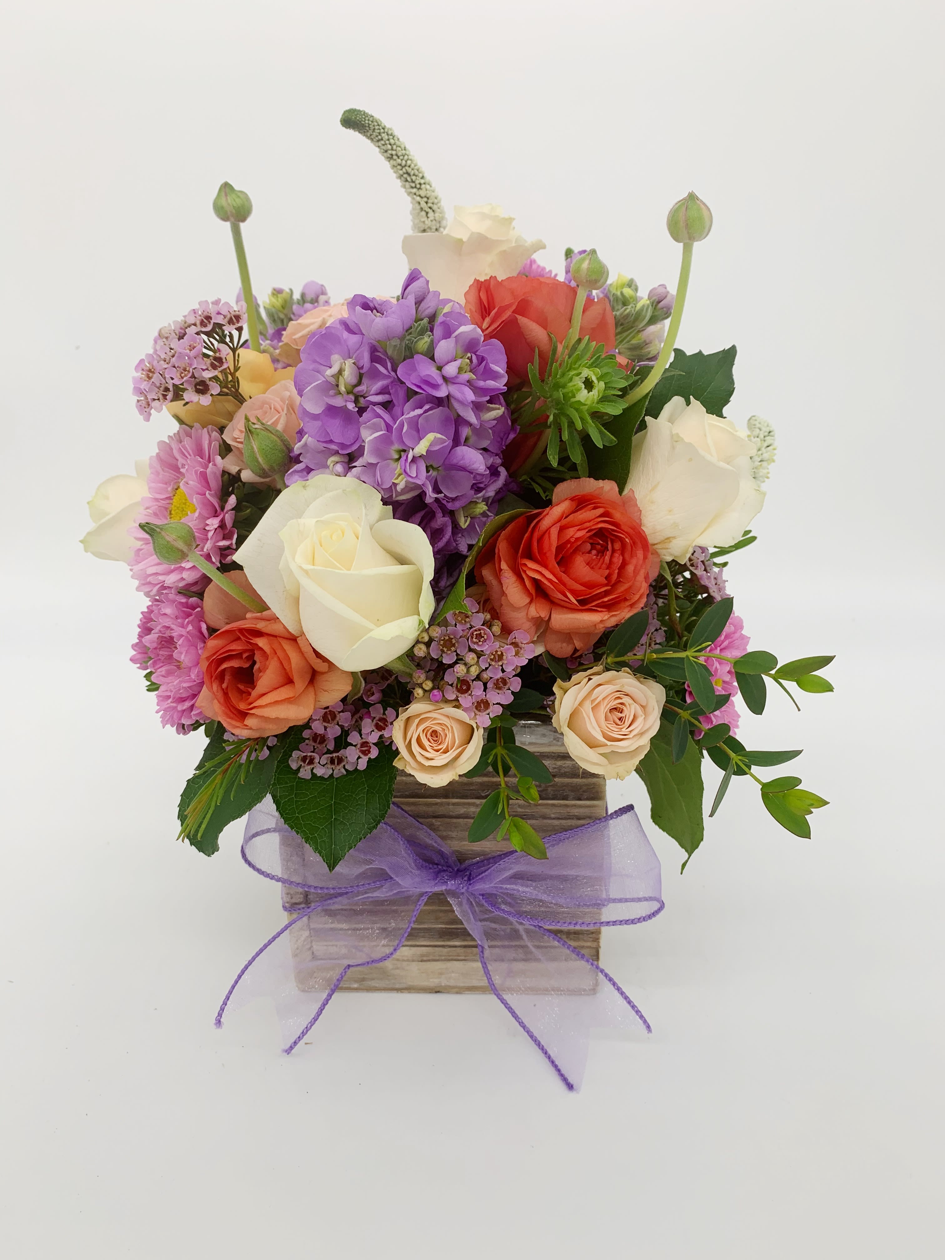 LF220 - Purple Pleasure - A beautiful all the way around arrangement.  This classic has white roses, ranunculus, spray roses, asters and stock. It's very feminine in a rustic wooden box. The purple ribbon is a perfect finishing touch.    Orientation:  All around