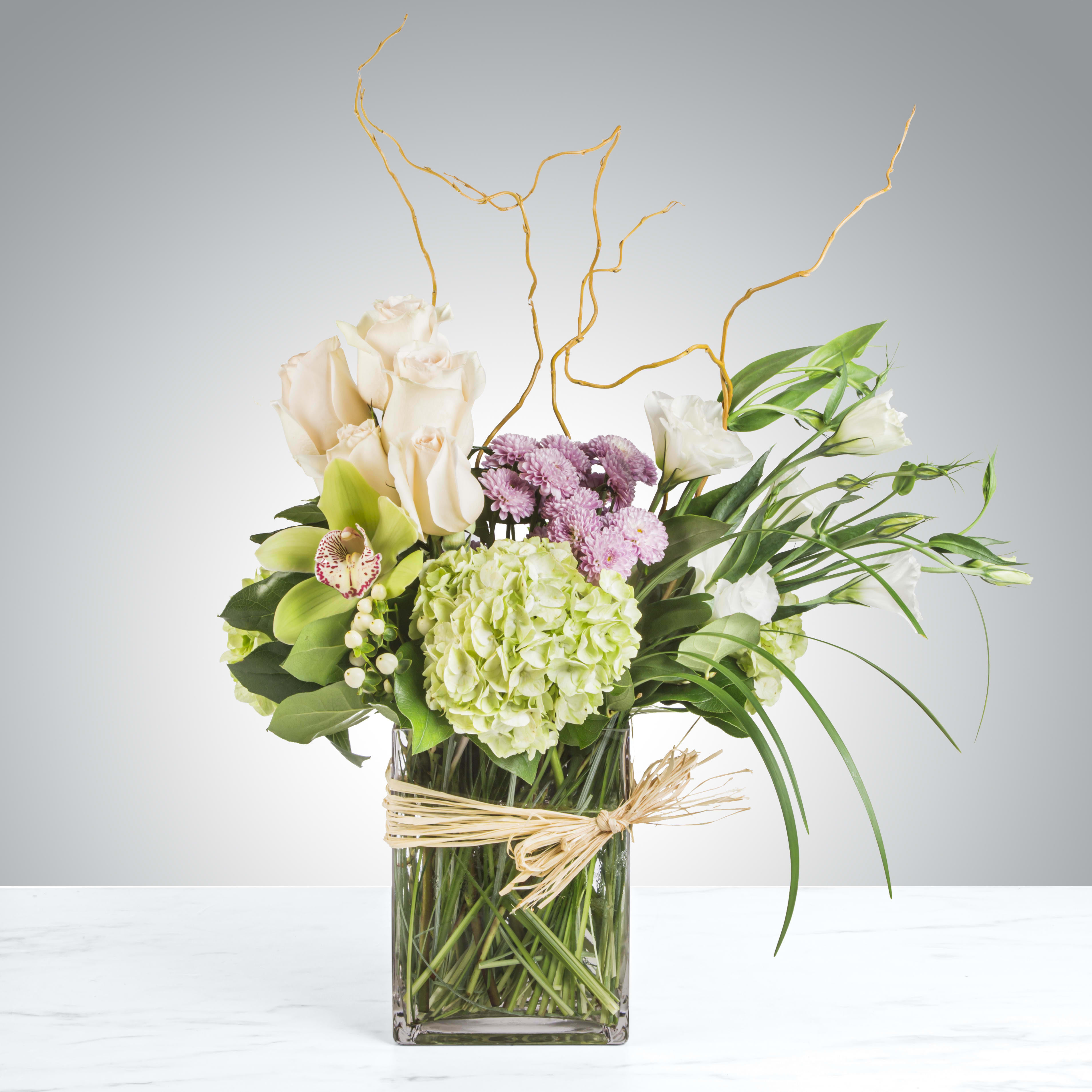 Riviera by BloomNation™ - This chic arrangement has graceful movement and artistic style. Filled with greens, orchids, roses and more, Riviera is the breath of fresh air everybody needs. Perfect for all occasions from new baby to happy birthday, this arrangement exudes taste and will be sure to impress.   APPROXIMATE DIMENSIONS 18&quot; W X 18&quot; H