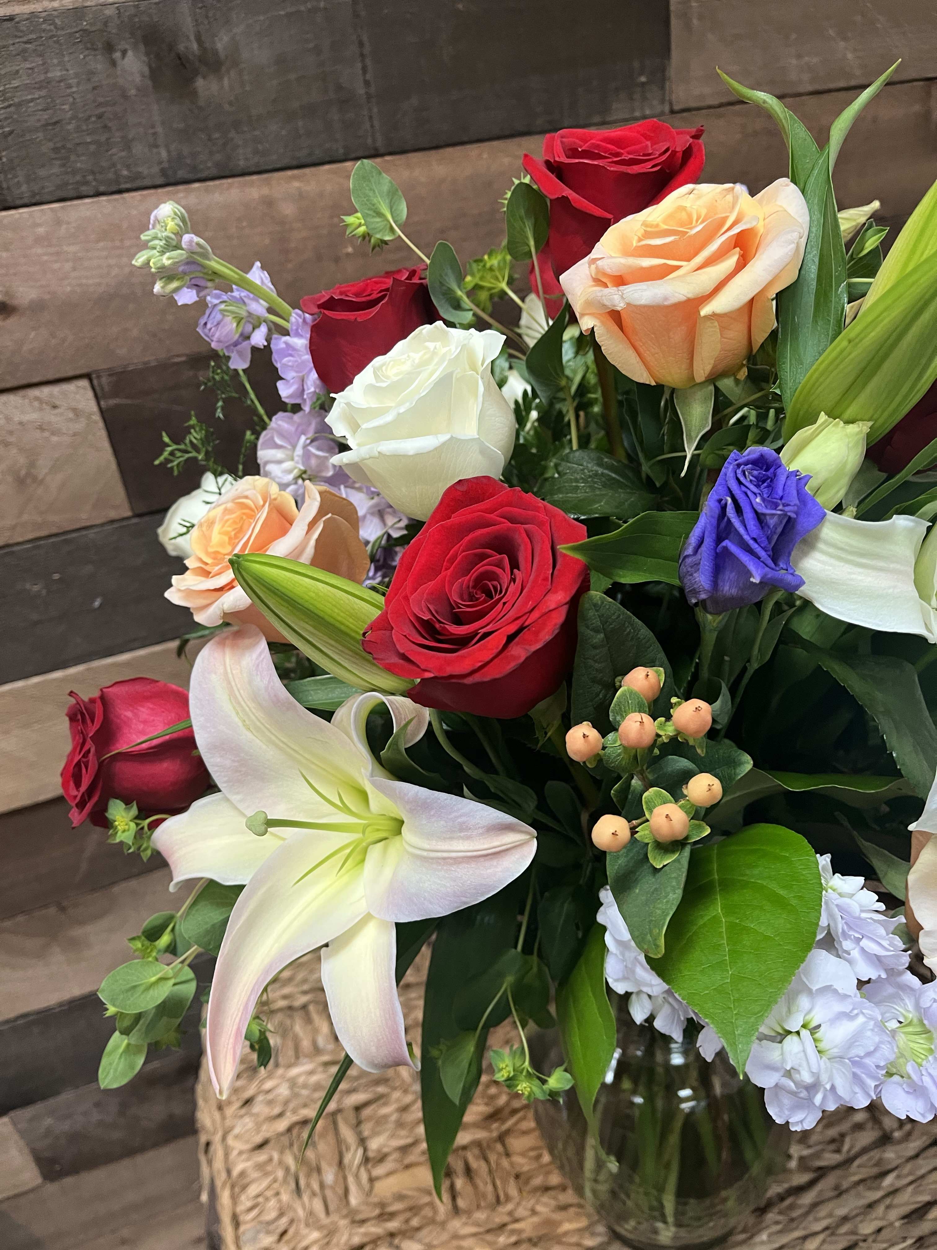 Harmony Hues - The &quot;Harmony Hues&quot; bouquet is a beautifully balanced arrangement featuring red, white, and peach roses, striking blue delphiniums, lush greenery, elegant lilies, and vibrant hypericums, creating a colorful and harmonious floral display.