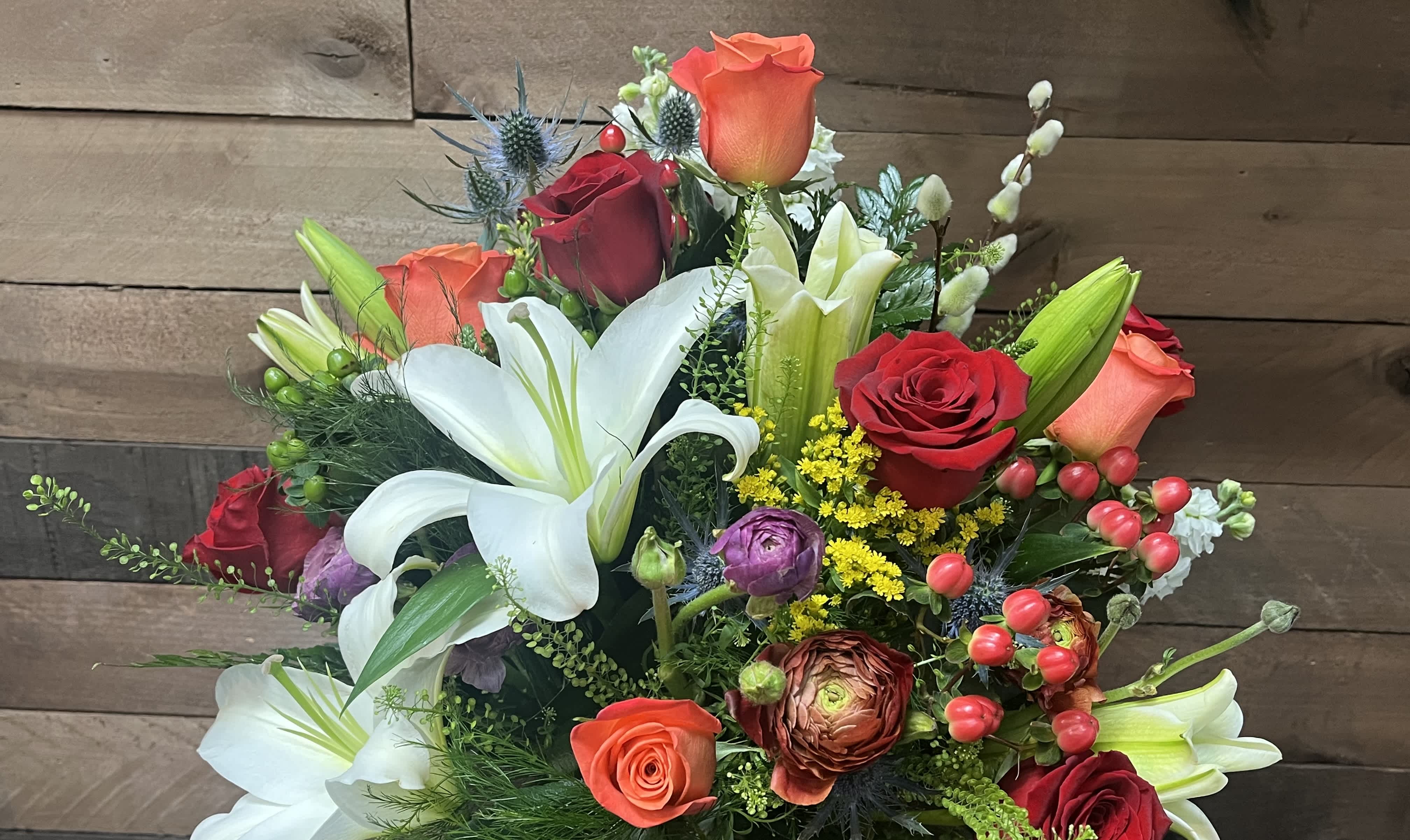 Tranquil Oasis - Lilies, roses, ranunculus, and stock nestled amidst lush greenery and punctuated by delicate eryngium.