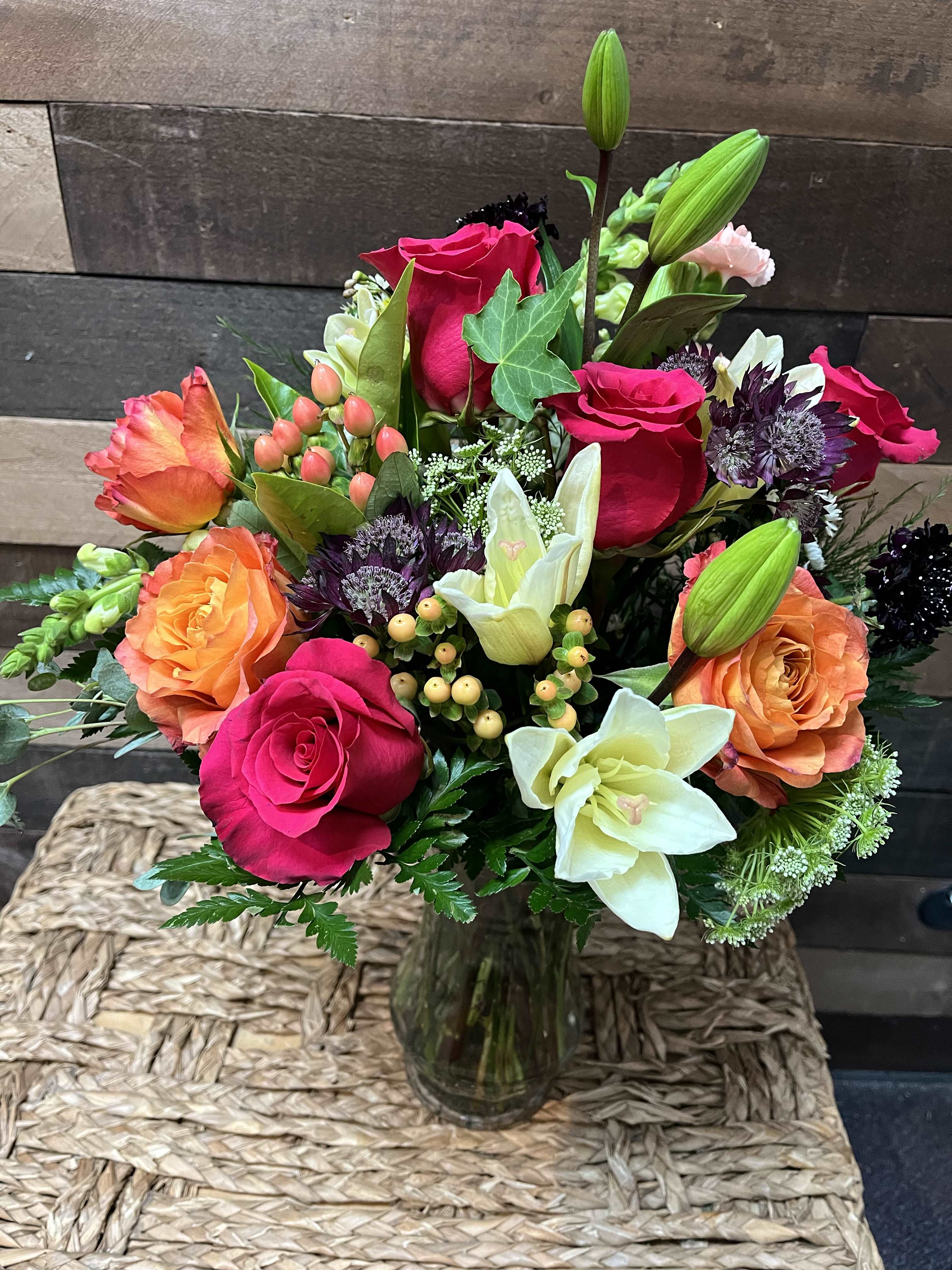 Radiant Elegance - Red and peach roses and lilies, accented by vibrant hypericums and scabiosa, nestled amid verdant greenery