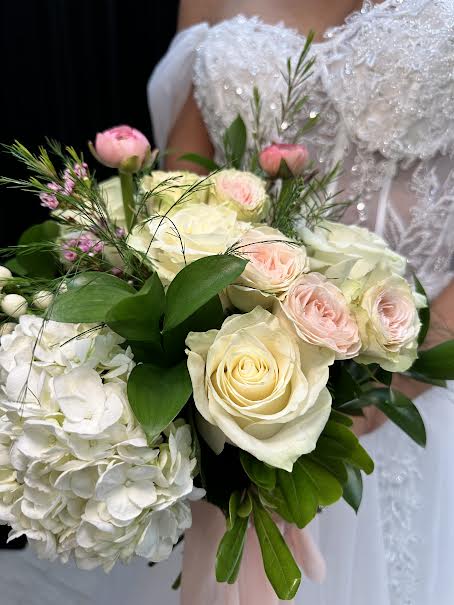 Snowy Serenade Bouquet - White roses and hydrangeas complemented by lush greenery, ranunculus, wax flower, and stock blooms.