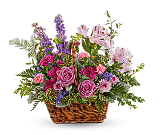Meadow Basket Bouquet Meadow Basket Bouquet - This lush rose arrangement is a basket of beauty to brighten any day! This bouquet features roses, alstroemeria, miniature carnations, larkspur, cushion spray chrysanthemums, lavender button spray chrysanthemums, purple sinuata statice, dusty miller, pitta negra, parvifolia eucalyptus, lemon leaf and leatherleaf fern. Delivered in a Rectangular Basket. Orientation: One-Sided