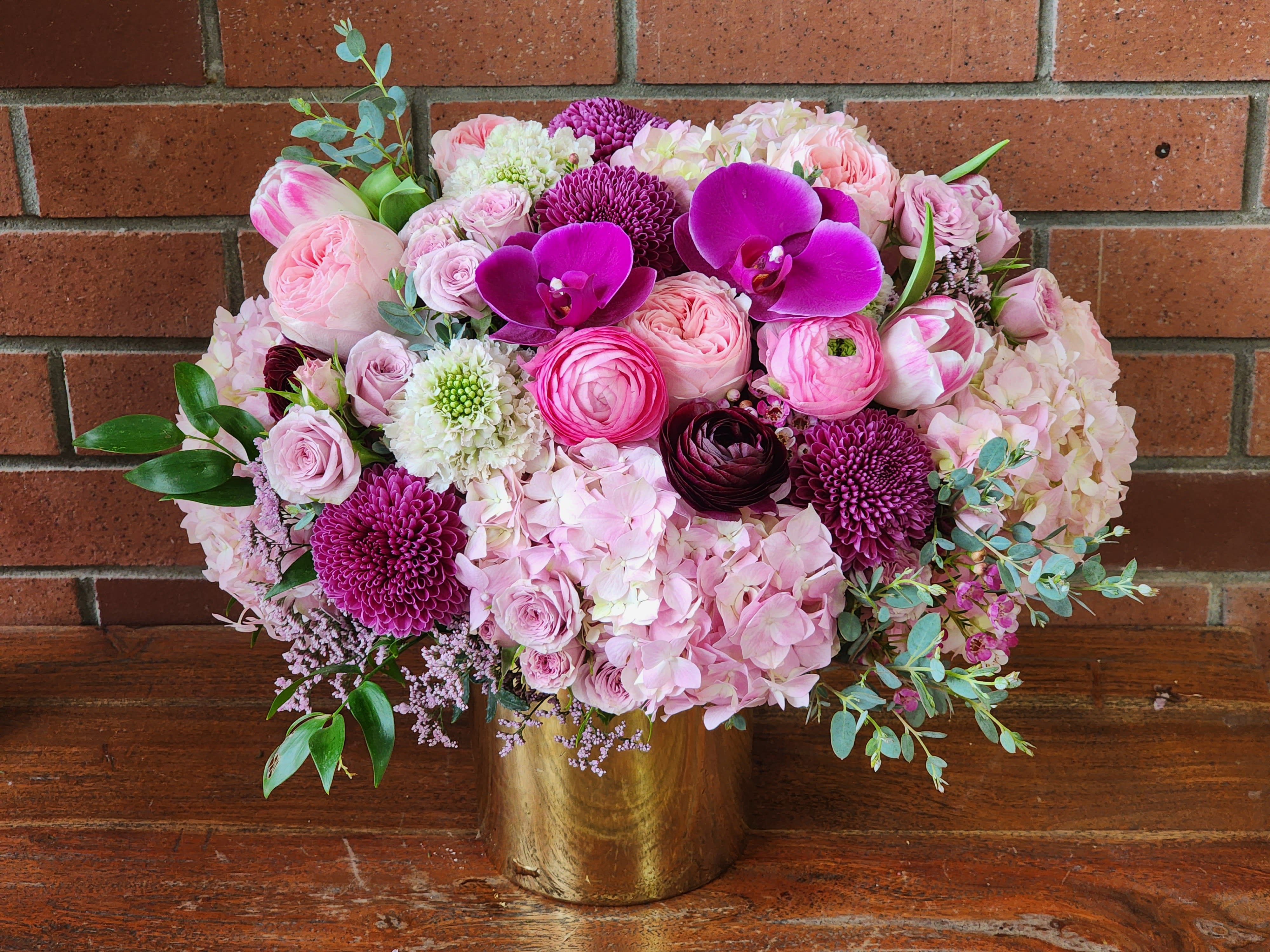 Pink Elegance Pink Elegance - Stylish premium blooms / hydrangea, scabiosa, orchids, garden roses, ranunculus, spray roses, tulips and more arranged in a beautiful gold cylinder vase