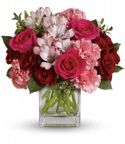 PINK PASSION - Tickle her pink with this sweetly chic mix. Arranged in a modern cube vase, this bouquet blends hot pink and deep crimson roses with the delicate notes of alstroemeria and carnations. Approx. 11 1/2 W x 11 1/2 H	 