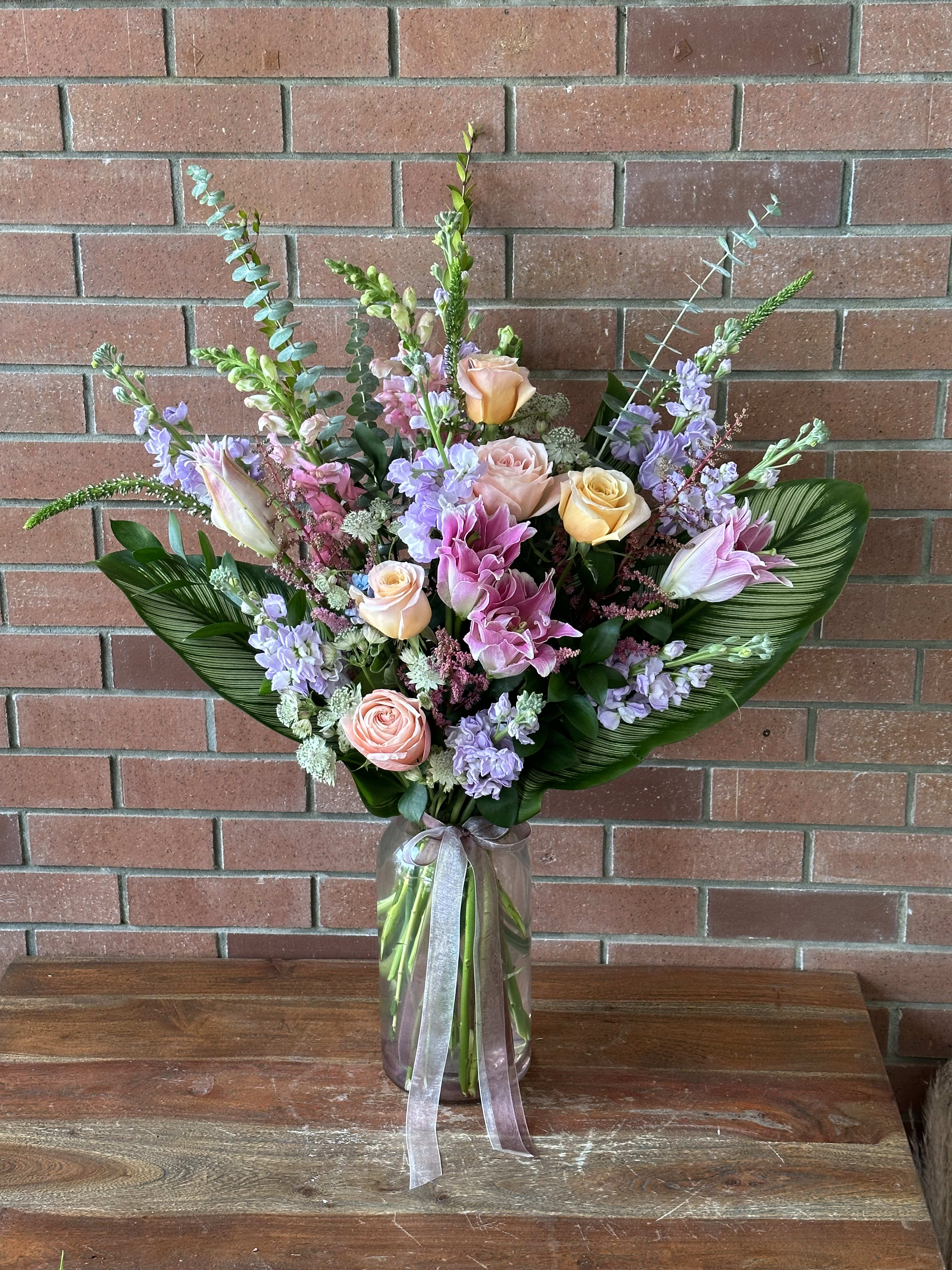 Love To Be Loved  - Tall and showy beautiful bouquet with pink lilies, lavender stock, roses, exotic leaves eucalyptus fillers in a beautiful high end light pink modern vase 