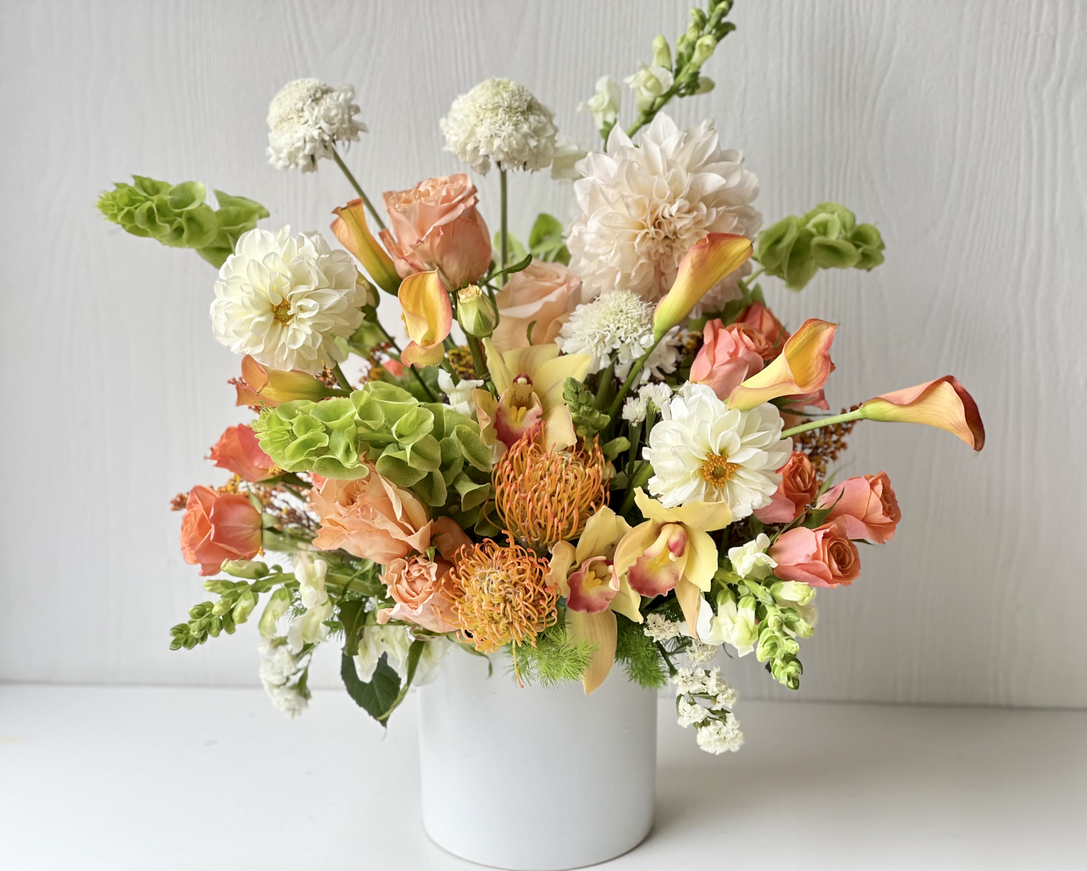 EC97 Best Mom Ever - This arrangement features energetic and joyful flowers that's perfect for brightening up your mother's space! This stunning bouquet features a delightful mix of peach, white, green and orange flowers such as roses, dahlias, cymbidium orchids, snapdragons, bells of ireland, pincushions, spray roses and calla lilies with fresh foliage. The floral arrangement is a perfect choice for any special occasion, from Mother's Day, birthdays to thank-you gifts. 