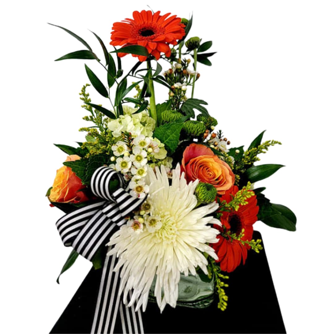 Orange Essences  - Short and full of color in a clear cube vase.  Vibrant oranges with a touch of white topped off with a mix of fillers and greenery. With each upgrade additional flowers will be added.  