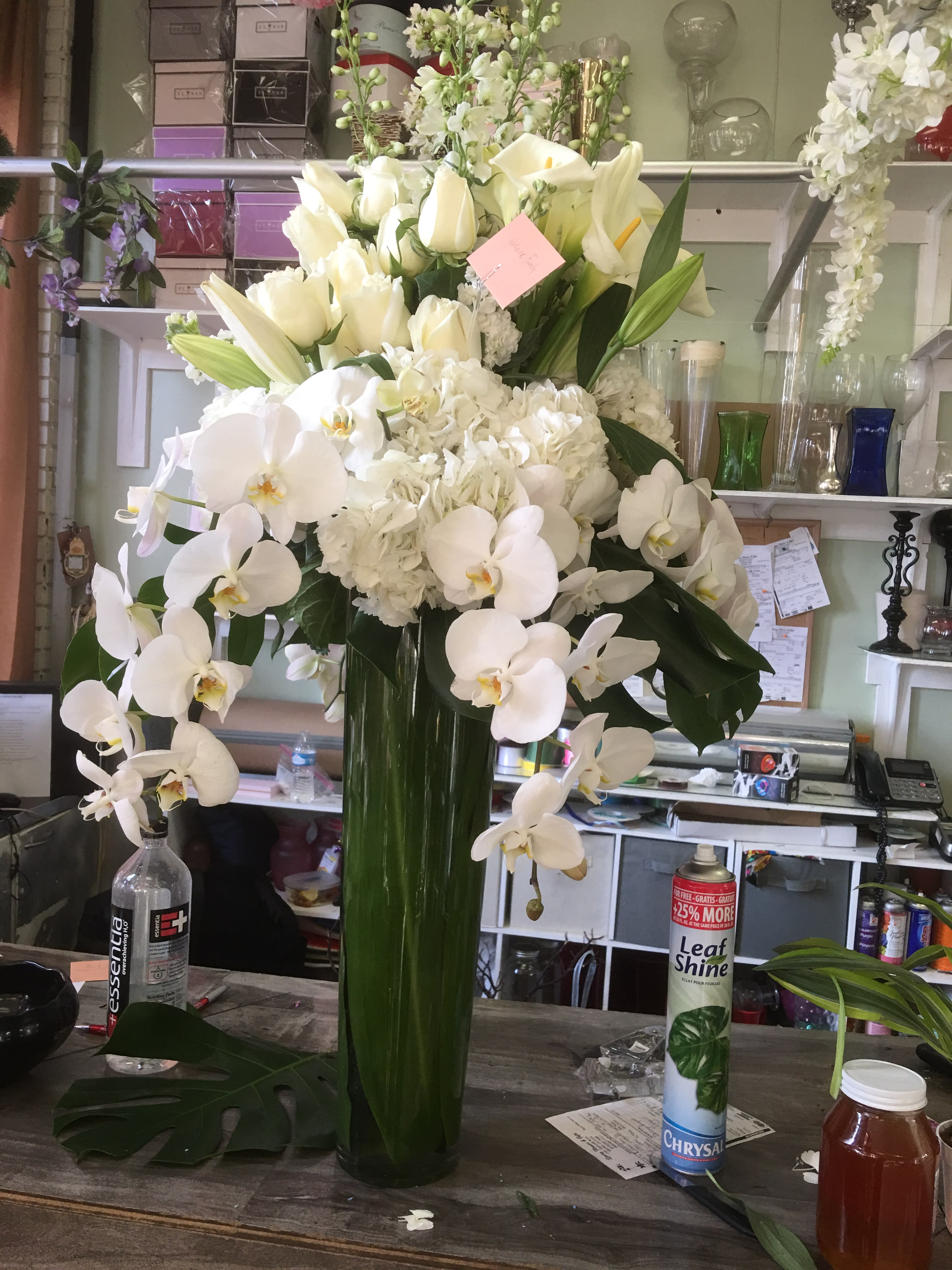 White Rose and Lily Elegance vase - Whites roses, Orchids and Lilies in a tall vase covered with green leaf