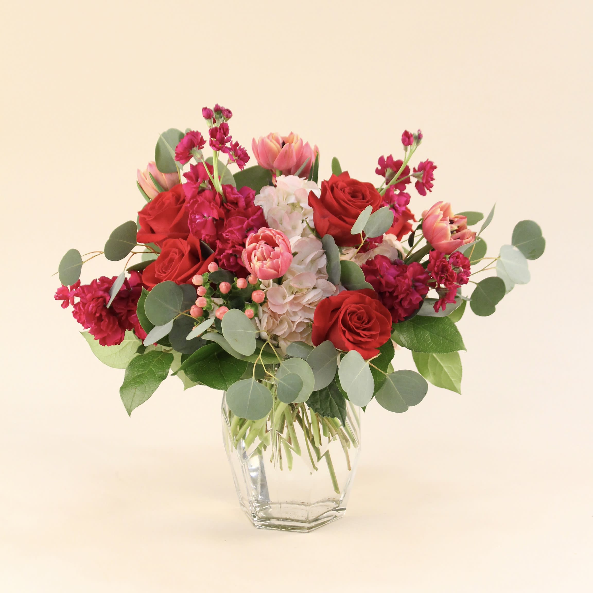 Forever Love - A romantic arrangement of pink, magenta and red flowers in a clear cylinder glass vase. Flowers may include roses, tulips,, hydrangeas, stock, coffee bean and  eucalyptus.  Vase dimension: 5” x 8&quot; This arrangement is approx. 15” tall and 17” wide.