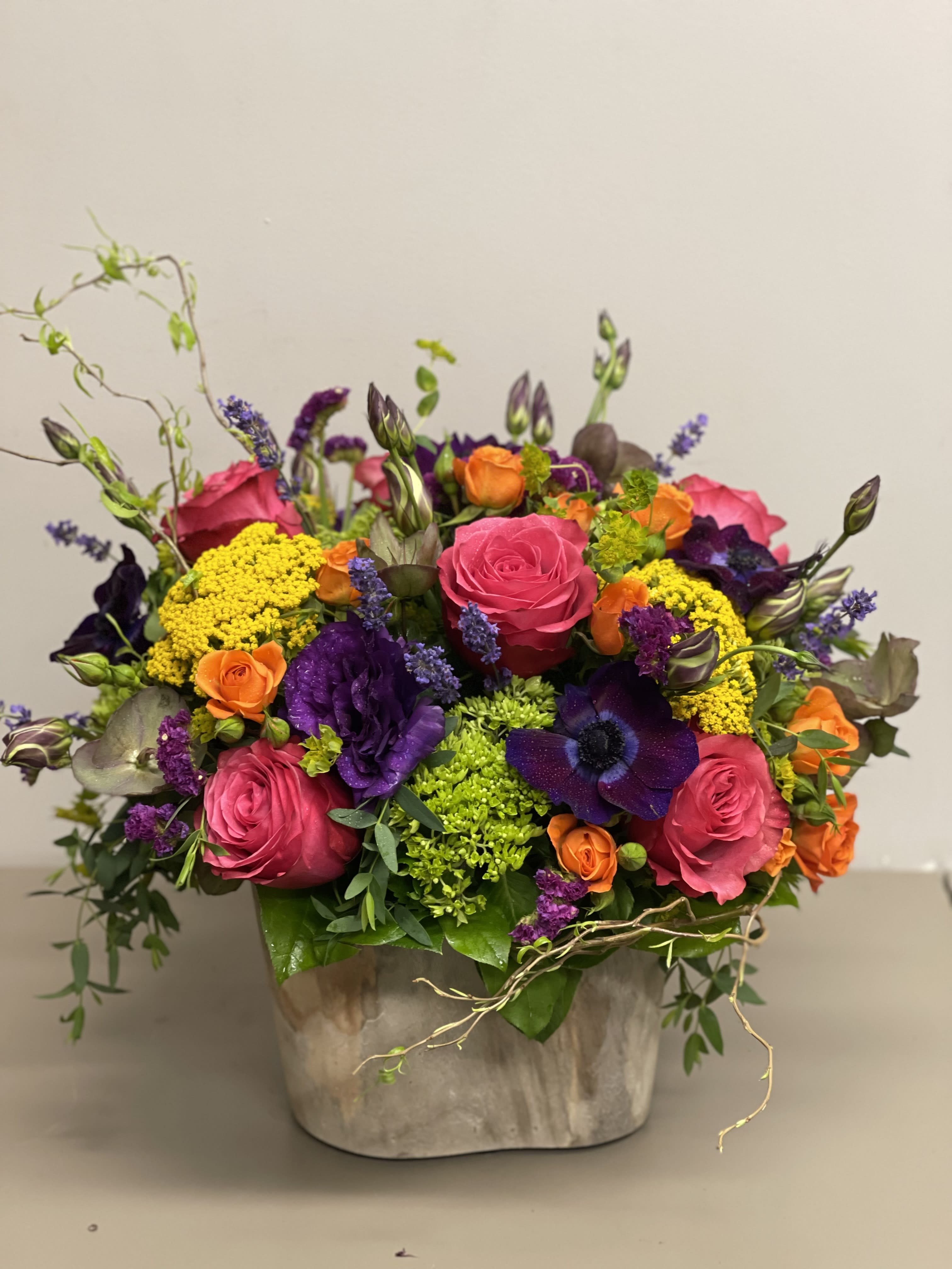 Brilliance - Stunning flower arrangement with Roses, Hydrangeas, Lisianthus , anemone and other seasonal flowers in bright jewel tones in a wooden rustic container.  