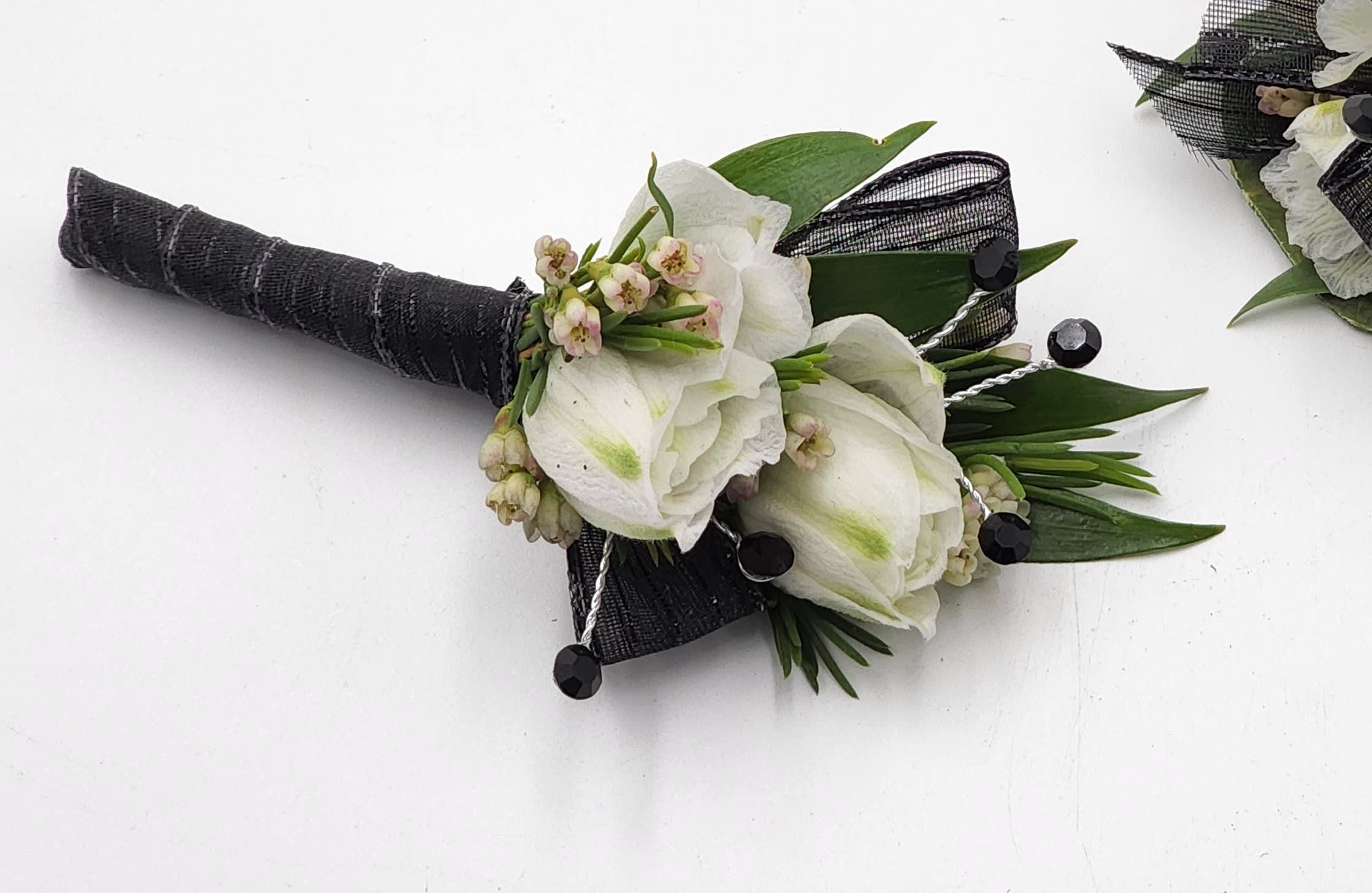 Masquerade Mystery Boutonniere Masquerade Mystery Boutonniere - A boutonniere featuring white larkspur, black ribbon & black rhinestones. Depending on availability of ribbon, may change slightly.