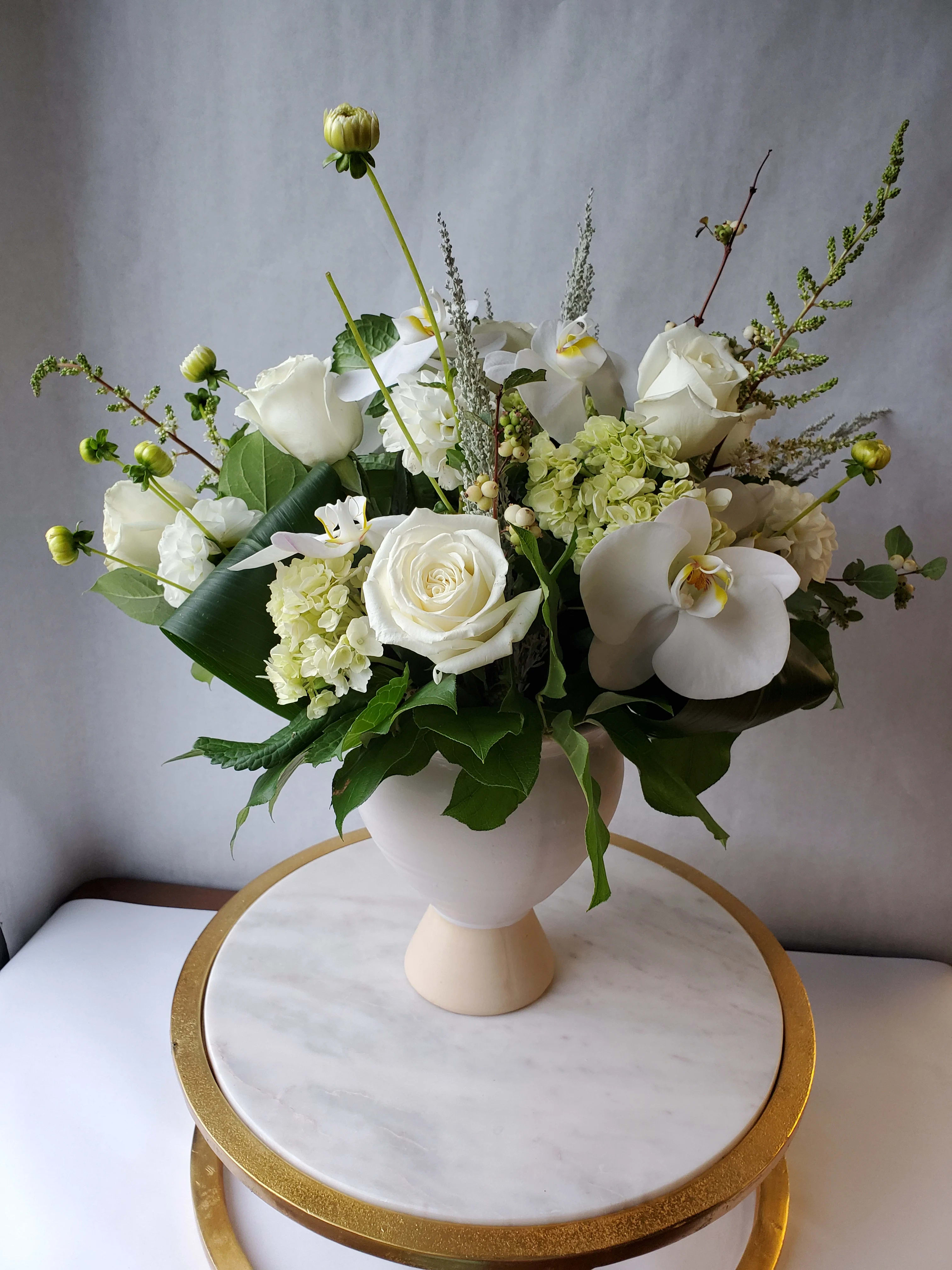 The Sophisticate - Tastefully compact this full-bodied arrangement lends an air of sophistication no matter the room in which it is placed.  With a timeless feel, this arrangement combines beautiful green and white tones to create a classic look.