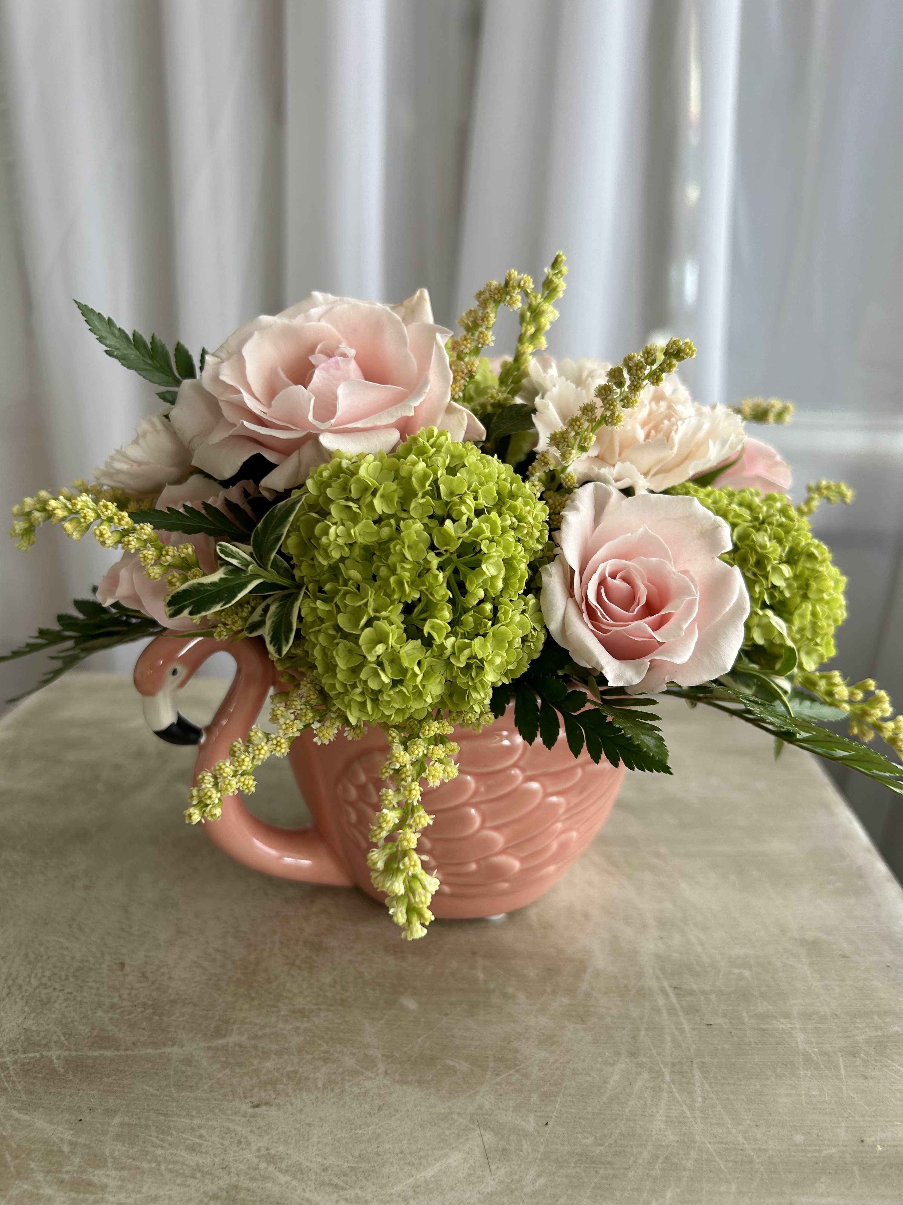 Flamingo Teacup - This flamingo teacup arrangement could be the perfect arrangement for your mother, or another special someone in your life. The standard size features pale yellows, pinks, and greens. As always. this design is subject to substitution based on what is in stock.