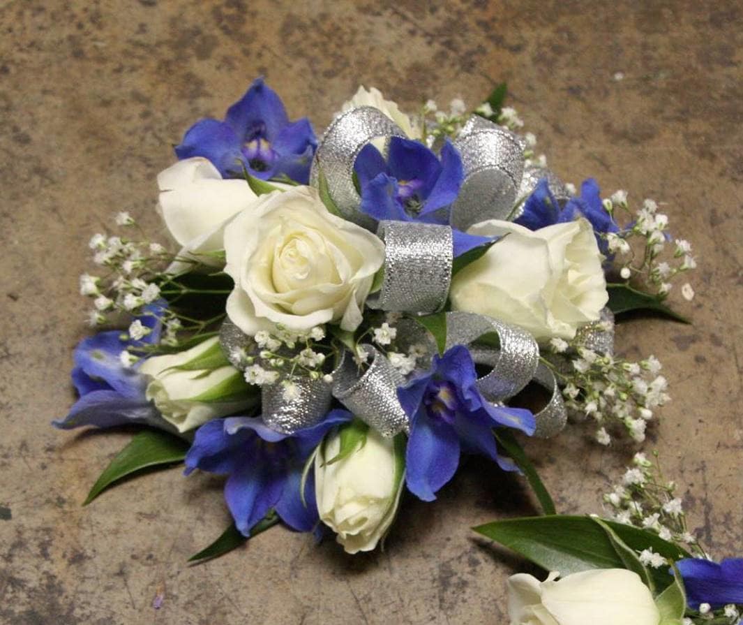 Blue Beauty Wristlet Blue Beauty Wristlet - Select this corsage of white spray roses, blooms of blue belladonna and babies breath with silver ribbon. ALL PROM FLOWERS ARE AVAILABLE IN COLORS PICTURED OR A CUSTOM SELECTION. CHOOSE YOUR FLOWER COLORS, RIBBON COLOR AND ANY ADD ONS. FOR QUESTIONS CALL A FRIENDLY SALES REPRESENTATIVE AT STRELITZIA FLOWER CO.