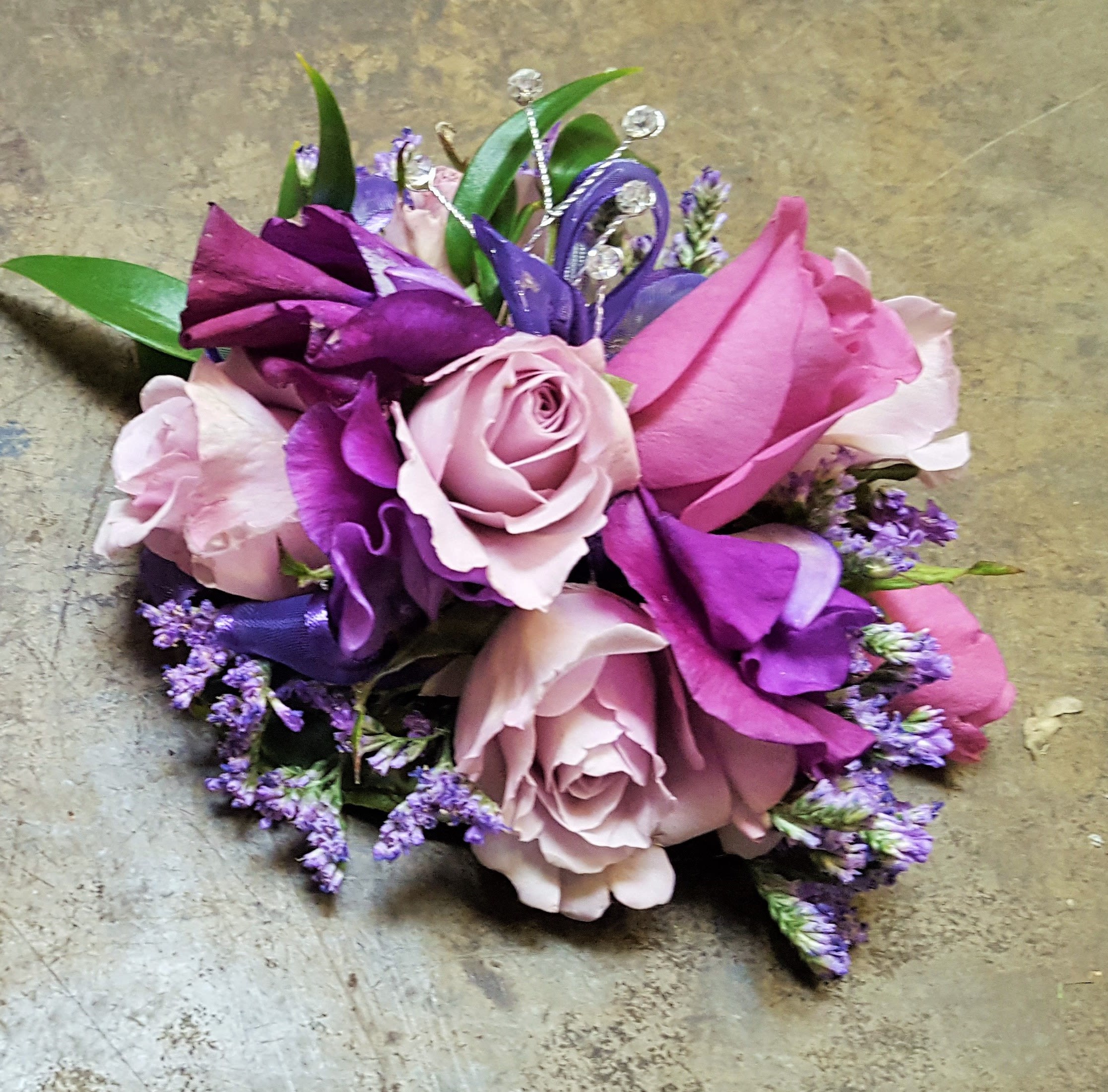 Lavender Luxurious Wristlet Lavender Luxurious Wristlet - Select this corsage of lavender and purple blooms. Flowers consist of lavender spray roses and purple sweet peas with purple ribbon and rhinestone accents.