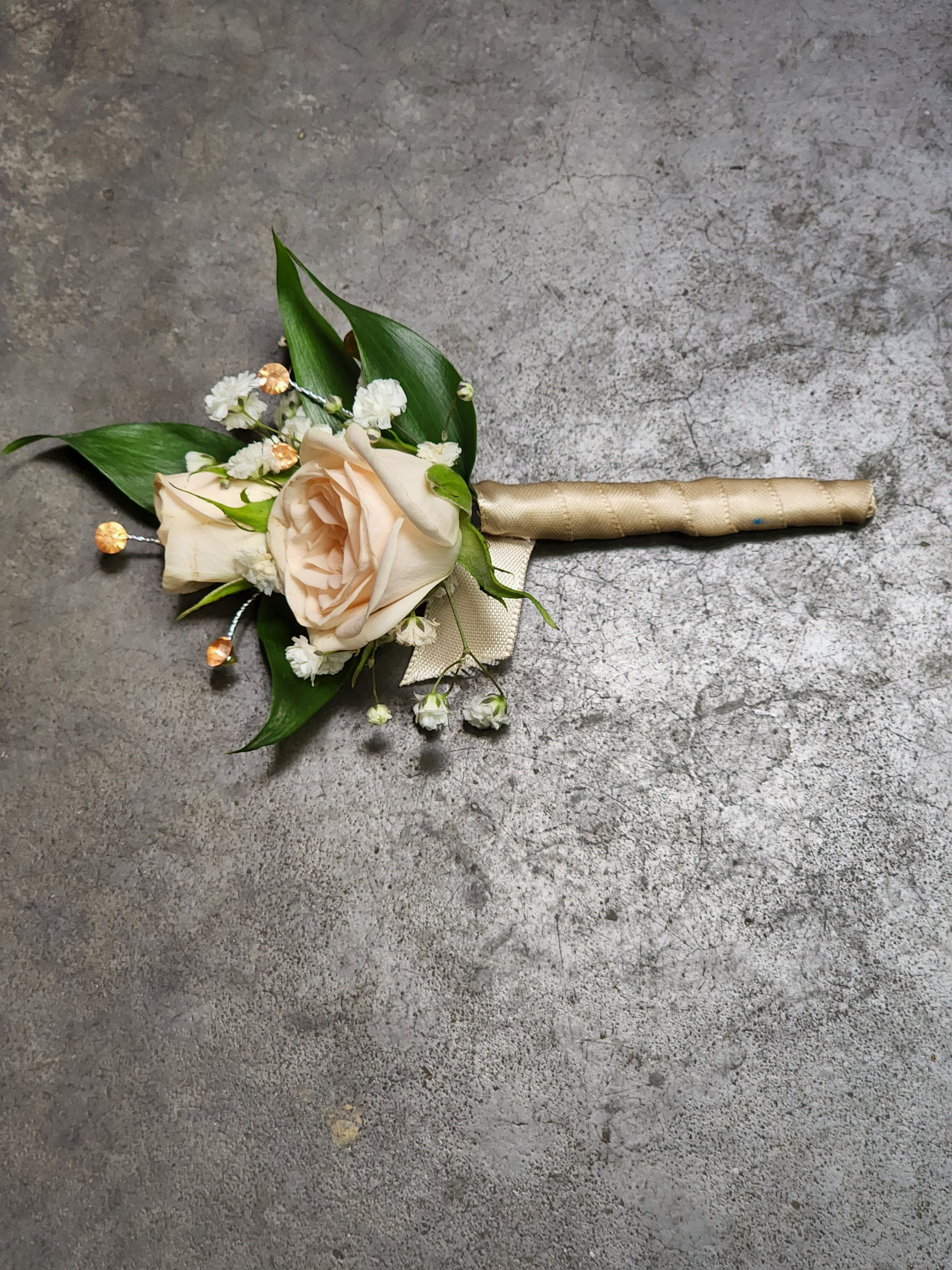 Peaches and Cream Boutonniere Peaches and Cream Boutonniere - A boutonniere featuring peach spray roses, peach ribbon, and peach rhinestones. Depending on availability of ribbon, may change slightly.