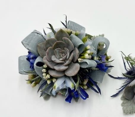Shades of Blue Wristlet Shades of Blue Wristlet - A wrist corsage featuring blue toned succulents, belladonna and blue-gray ribbon. Depending on availability of ribbon, may change slightly.