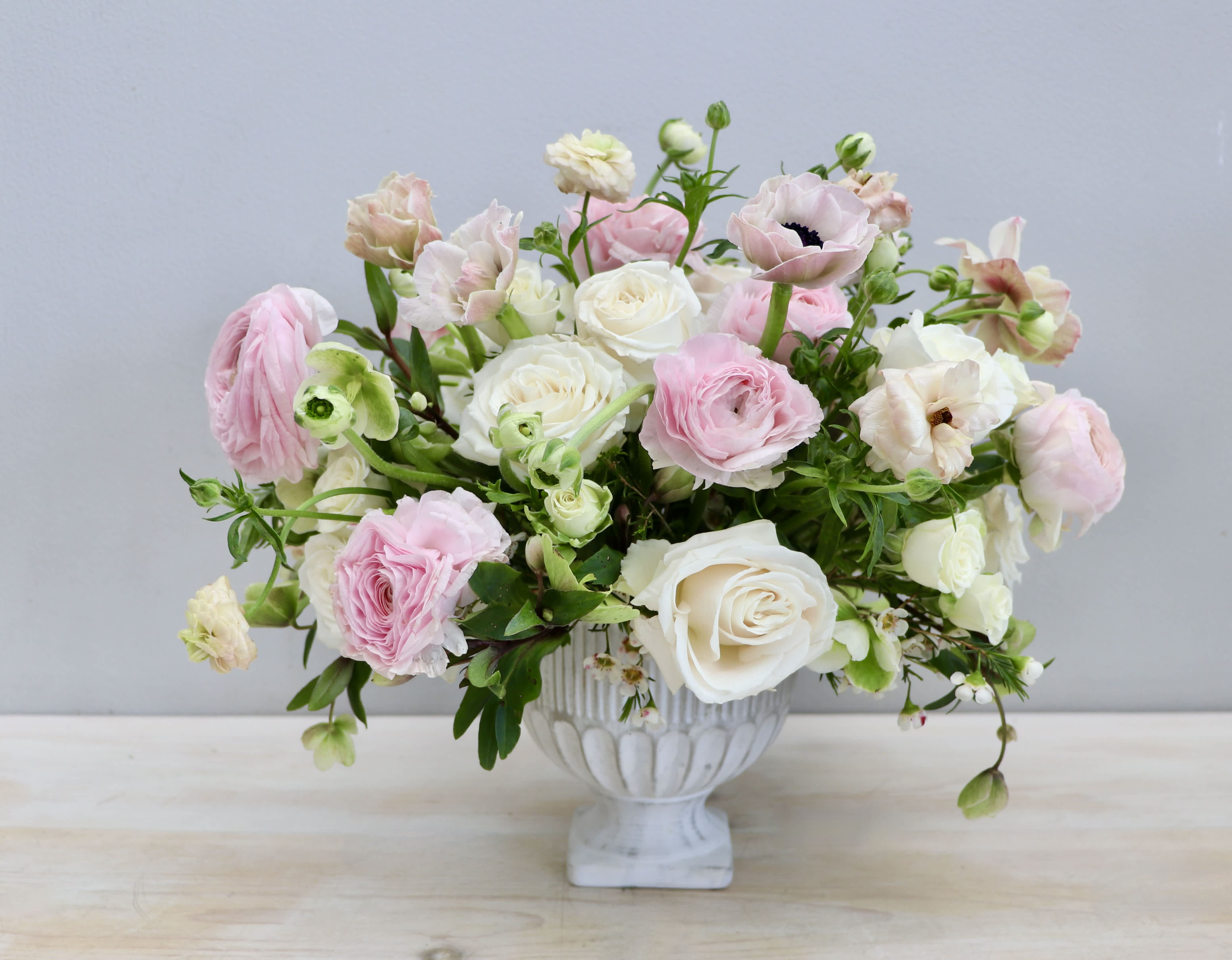 Blush Beauty - My Glendale Florist - Blush Beauty is made with a mix of our favorite light pink and white flowers in this classic stone vessel. This arrangement includes light pink ranunculus, anemone, hellabore, and white large and small roses.