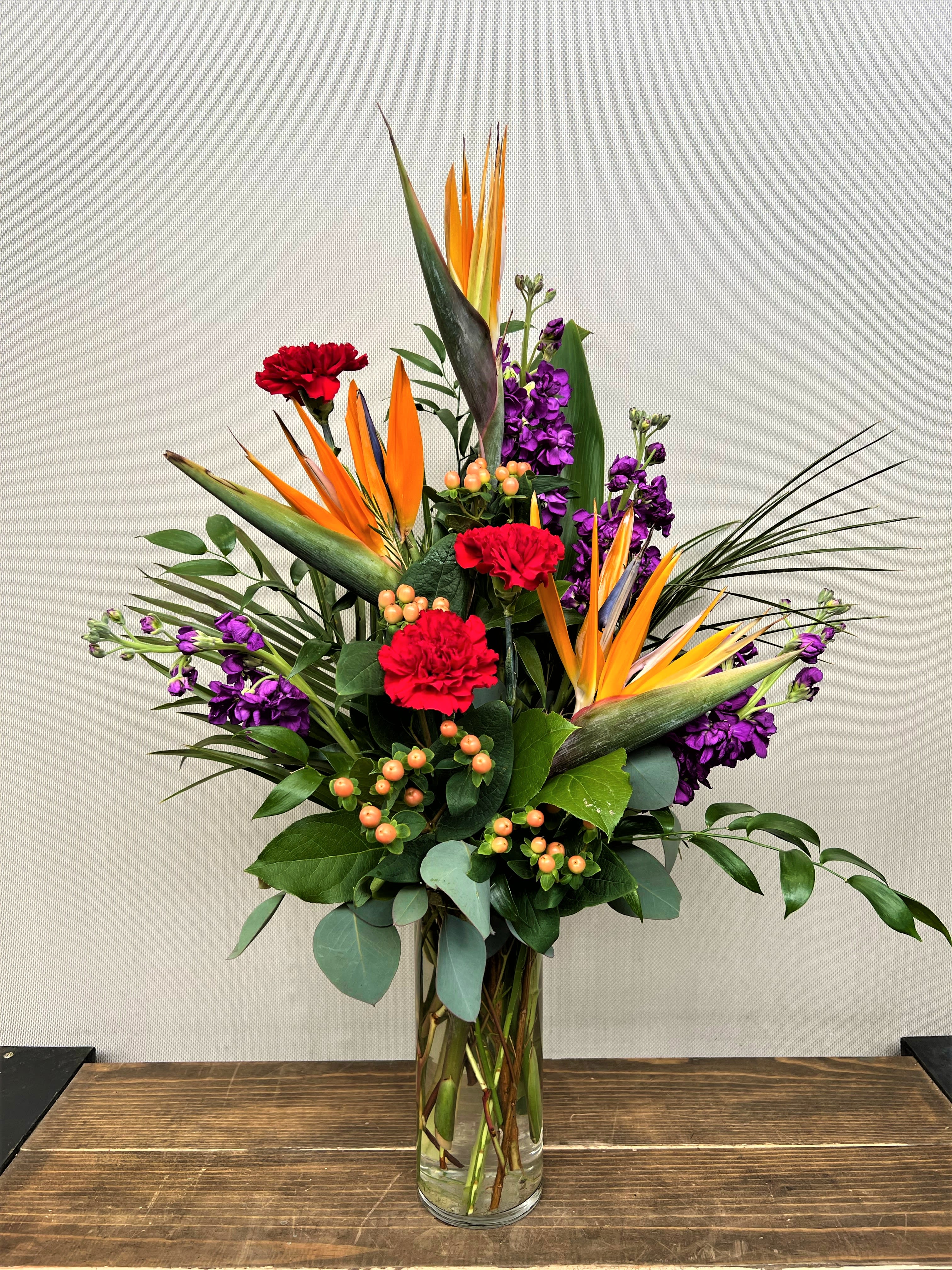 Mom's Paradise - Transport mom to a tropical paradise with this lush arrangement of Birds of Paradise, accented with fragrant stock, sweet carnations, and bright hypericum berries all in a cylinder vase.