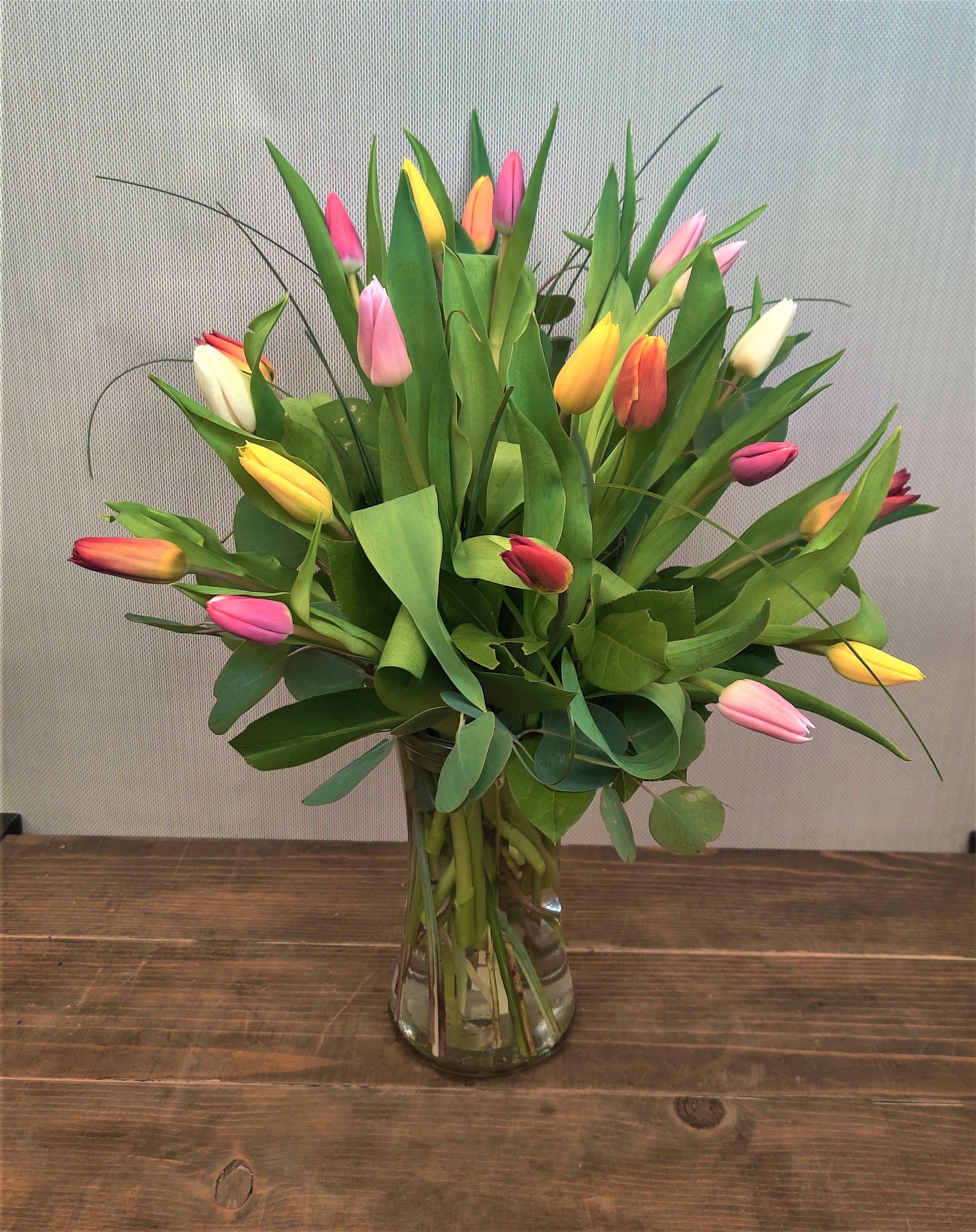 Tenderly Tulips- 20 stems- assorted colors  - Picked fresh from the farm, this tulip Bouquet is a jubilant expression of the changing seasons! Celebrate the day with our finest tulips in a bright assortment of colors, seated in a clear glass vase creating a dazzling bouquet that showers them with your affection. 