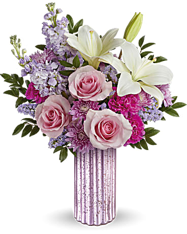 Sparkling Delight Bouquet - Sparkle up her Mother's Day with Teleflora's Sparkling Delight Bouquet, featuring a breathtaking bouquet of roses, lilies, and lavender accents elegantly presented in a sculpted glass vase with a lavender mercury-inspired finish.. Pink roses, white asiatic lilies, hot pink carnations, lavender stock, lavender cushion spray chrysanthemums, and sinuata statice are arranged with huckleberry in Teleflora's Sparkling Delight vase, creating a stunning Mother's Day bouquet. Orientation: All-Around  SUBSTITUTION POLICY – Always deliver the freshest flowers! Please note the bouquet pictured reflects our original design.  If the exact flowers or container in this arrangement are not available, our local florists will create a beautiful bouquet with the freshest available flowers.