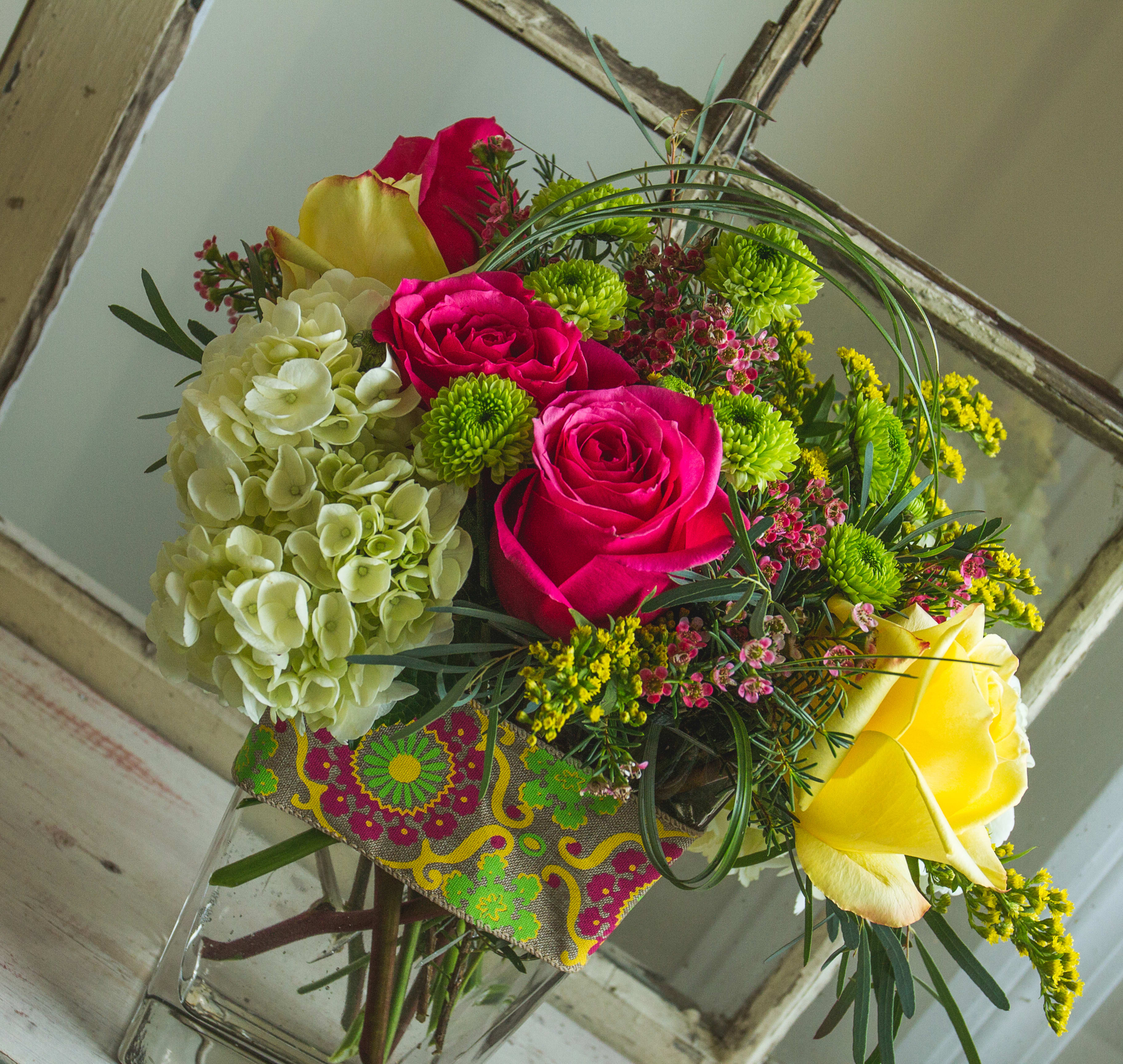 Exuberant! - Vibrant green, yellow, and fuchsia flowers and filler adorn a cube vase with designer ribbon. 