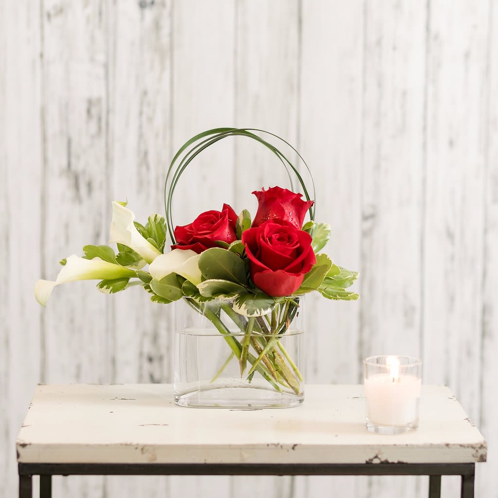 Revolution - An arrangement of calla lilies and classic red roses is designed in a contemporary style.  Petite in size, it's perfect for the desk, dorm or coffee table of anyone who appreciates a modern style!  Approximate Dimensions: 10&quot; H x 12&quot; W